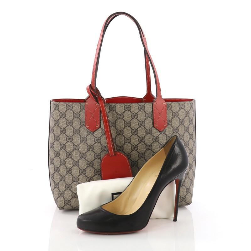 This Gucci Reversible Tote GG Print Leather Small, crafted from brown GG print leather, features tall slim handles and subtle Gucci logo at the front. Its wide top opens to a reversible red leather interior. **Note: Shoe photographed is used as a