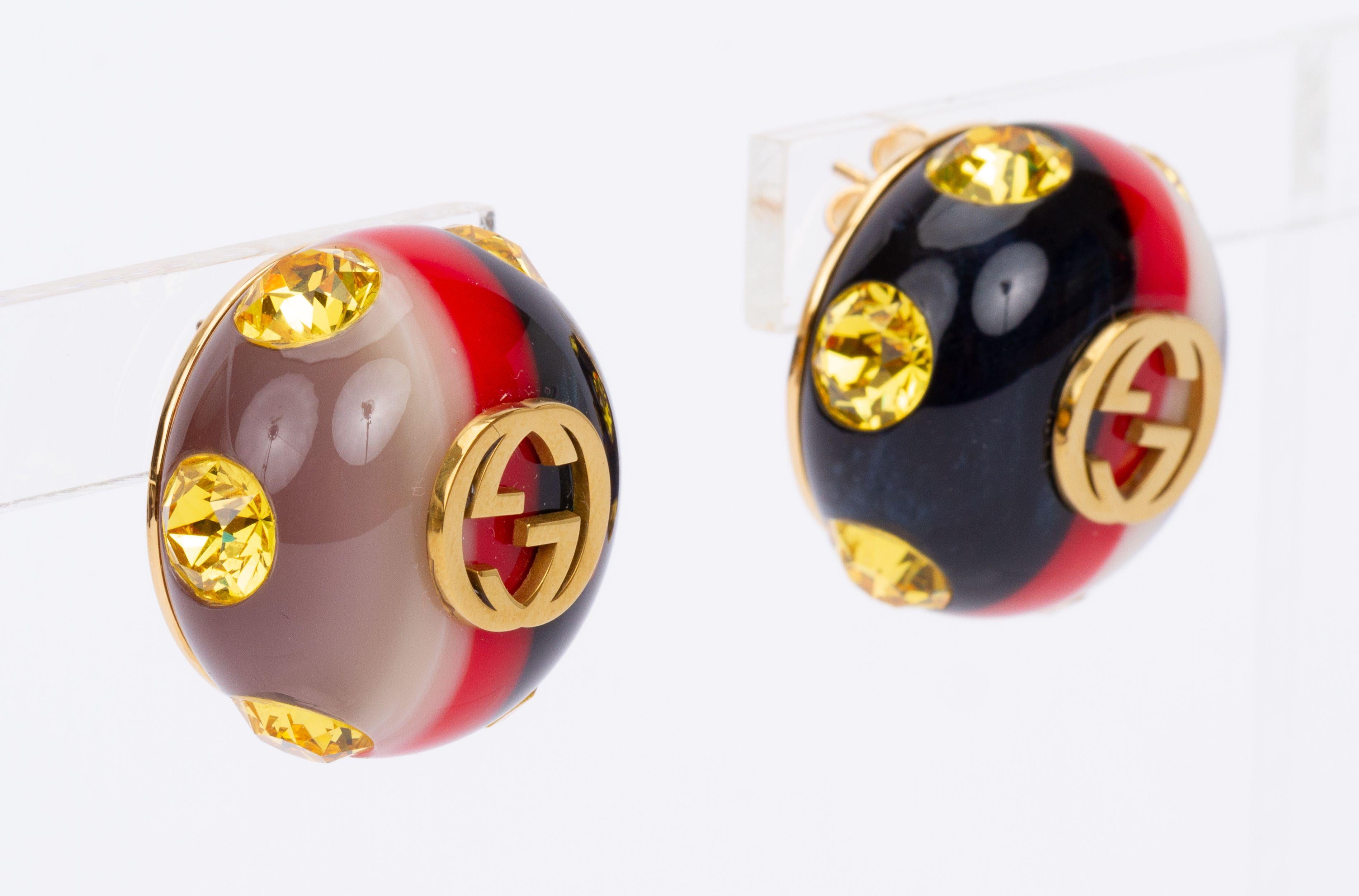 Round Gucci earrings with the GG logo in the center and a striped coloring surrounded by yellow crystals. They're brand new and come with the original box and dust cover.