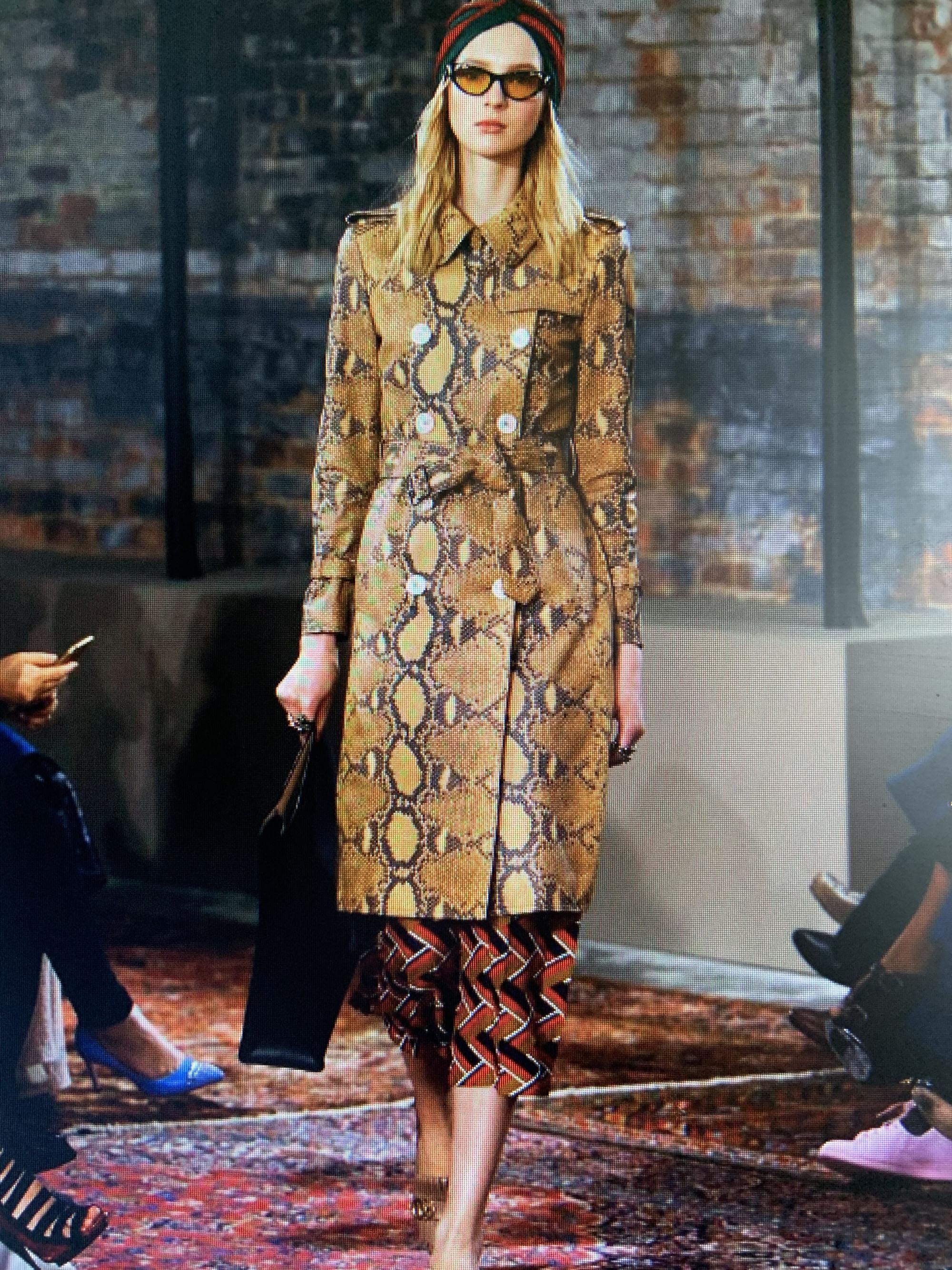 An exceptional statement trench coat from Gucci, crafted in Italy from luxe lamb leather with a bold python-print motif—an arresting blend of texture, color, and couture craftsmanship.

Constructed from butter-soft lamb leather, the coat is printed