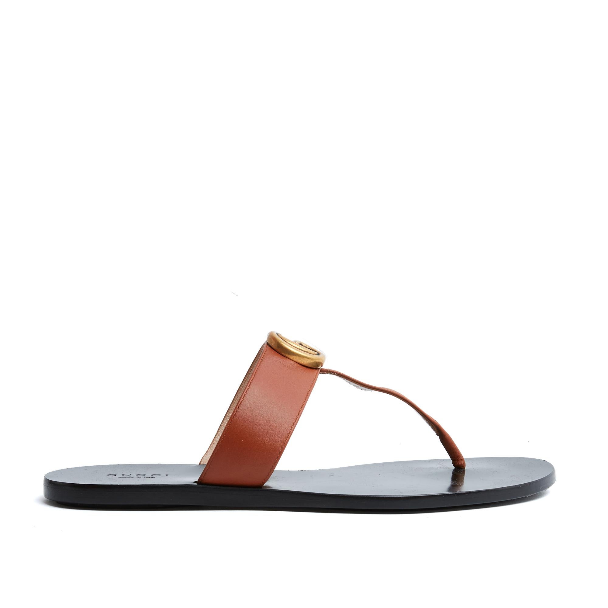Gucci GG or Marmont thong sandals in camel leather with an antique gold metal GG motif. Black leather insole and outsole lined with black rubber, 