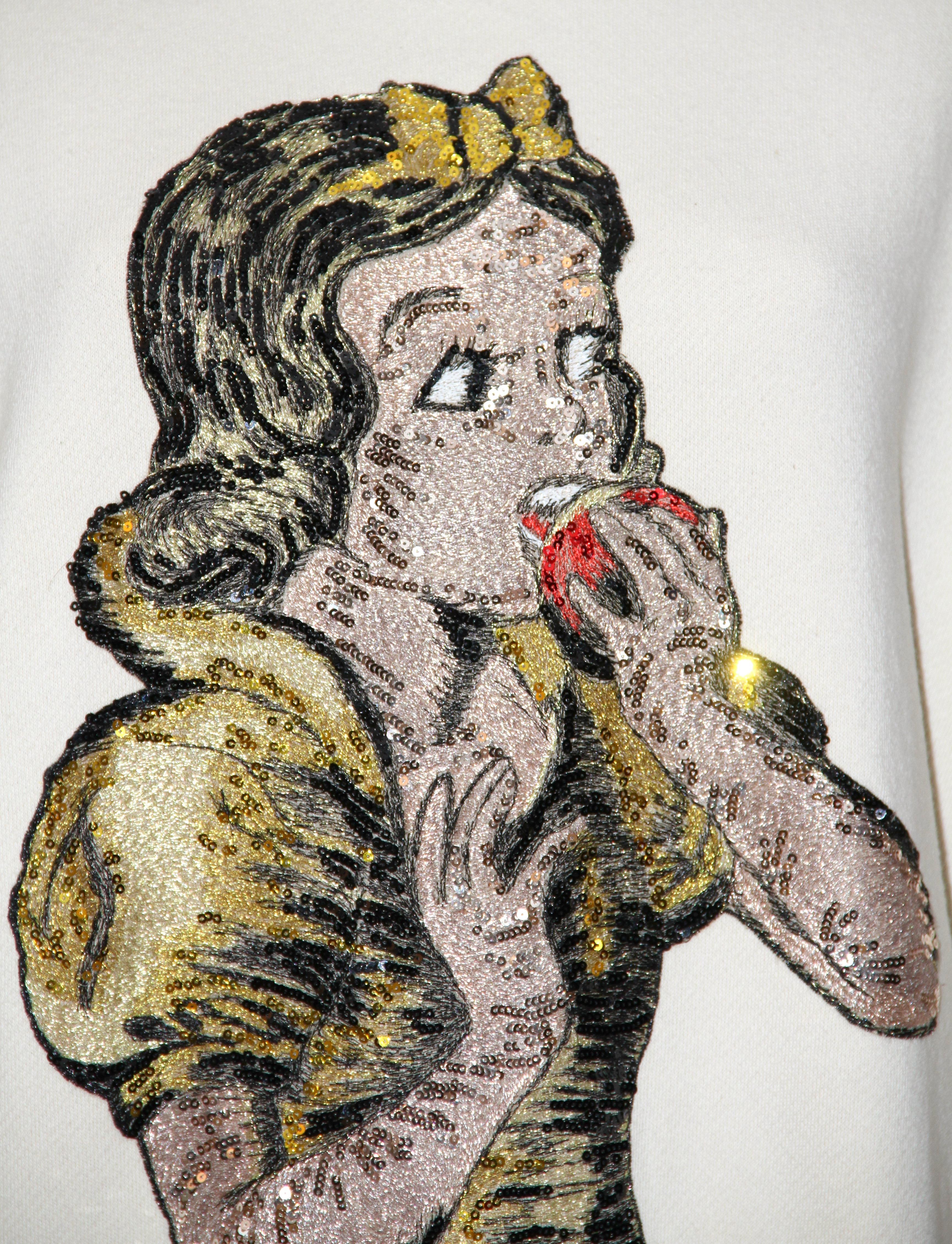 Crafted in a beautiful neutral ivory color cotton, this Snow White Sweatshirt from the house of Gucci is reviving childhood memories ! 
It features a multi-colored sequin embellished embroidery of Snow White in the front and a black Gucci lettering