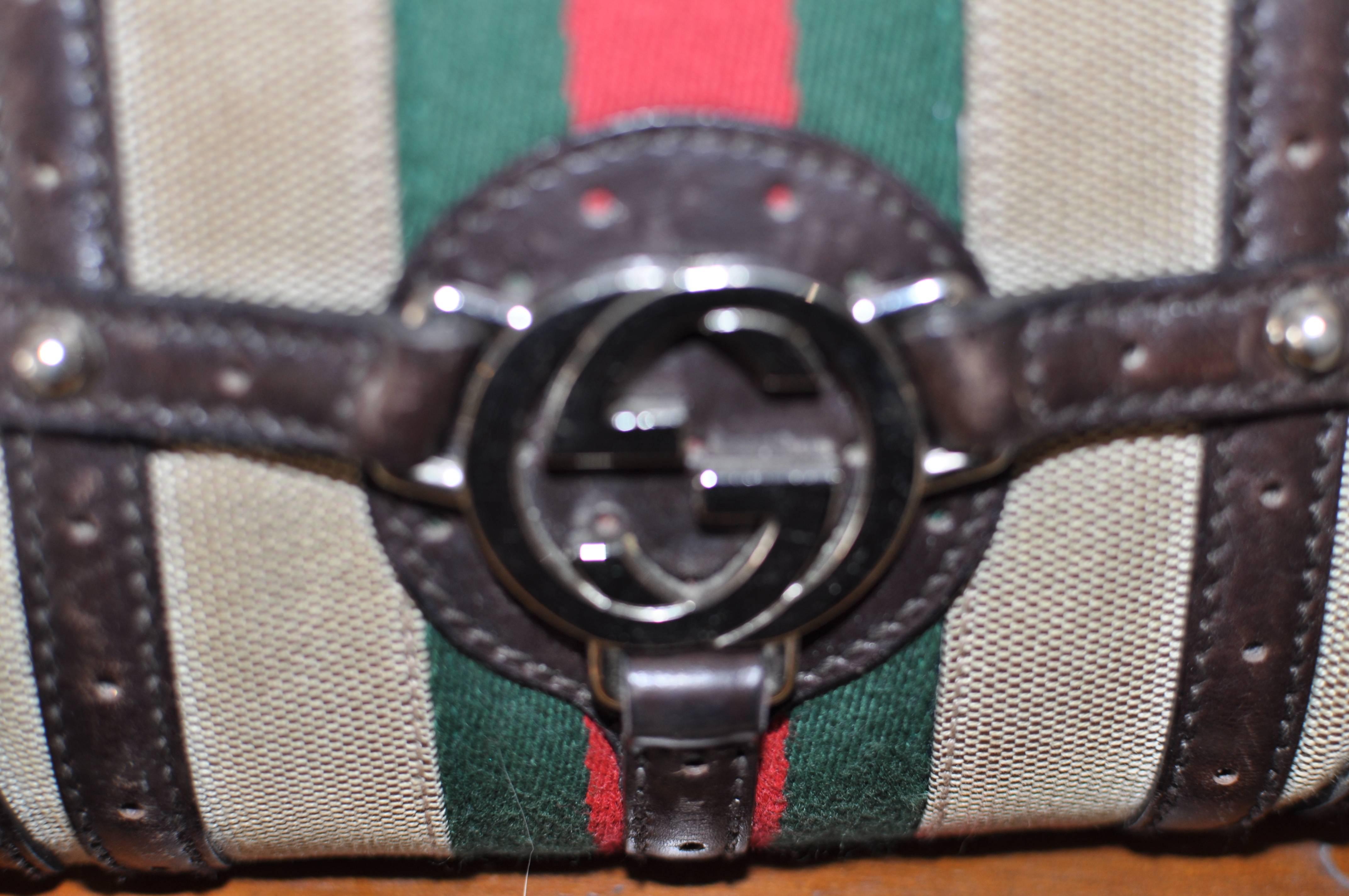 Features include a silver double G in front anchoring vertical and horizontal leather straps; top zip closing; one slot pocket; Gucci logo lining; Certificate of Authenticity and a customized purse adornment.

There is some scuffing to the corner