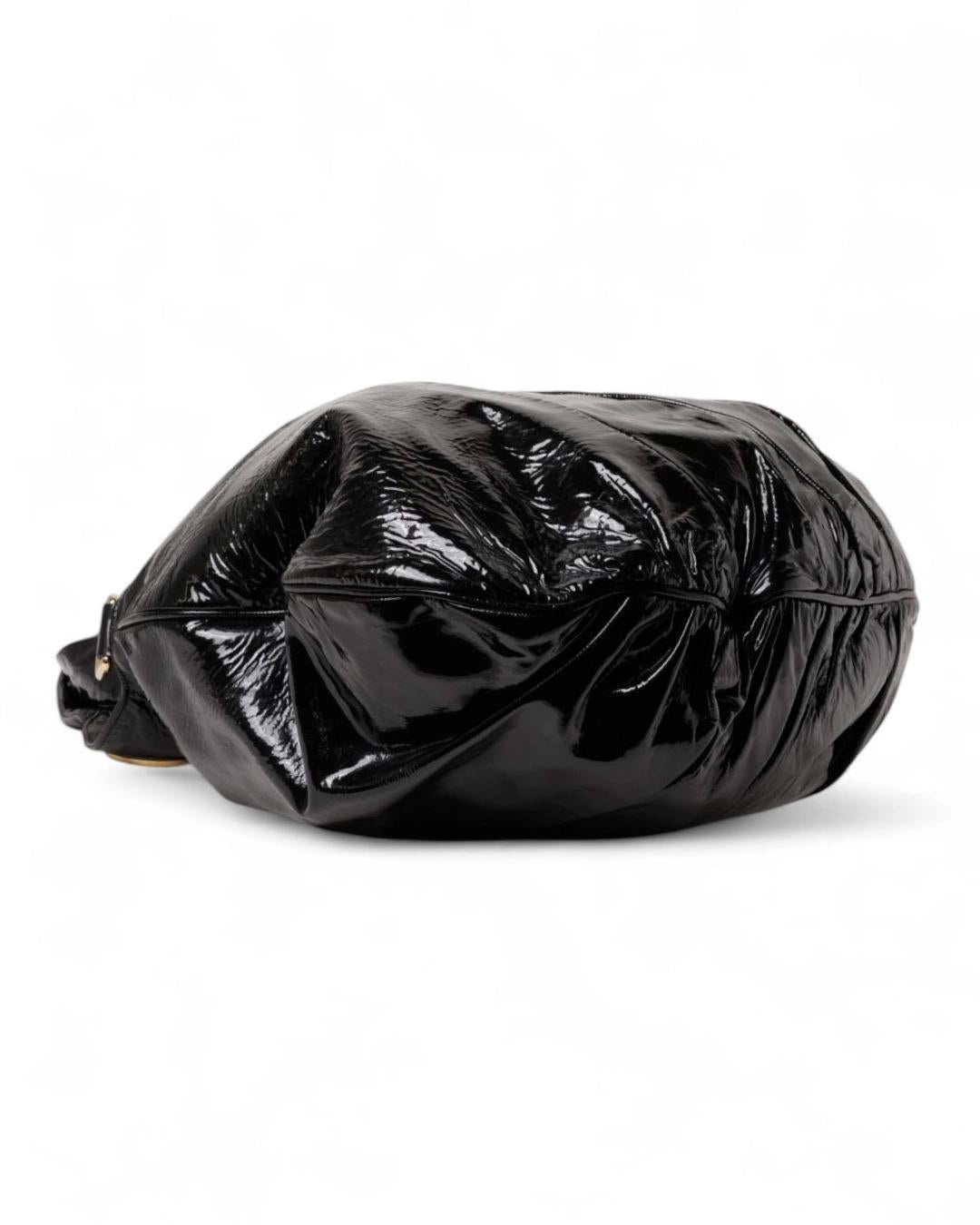 Borsa firmata Gucci, linea Hysteria nella misura large, realizzata in pelle verniciata nera con hardware dorato. Dotata di una chiusura interna a bottone calamitato, internamente rivestita in tessuto logato con comode tasche, la borsa è molto