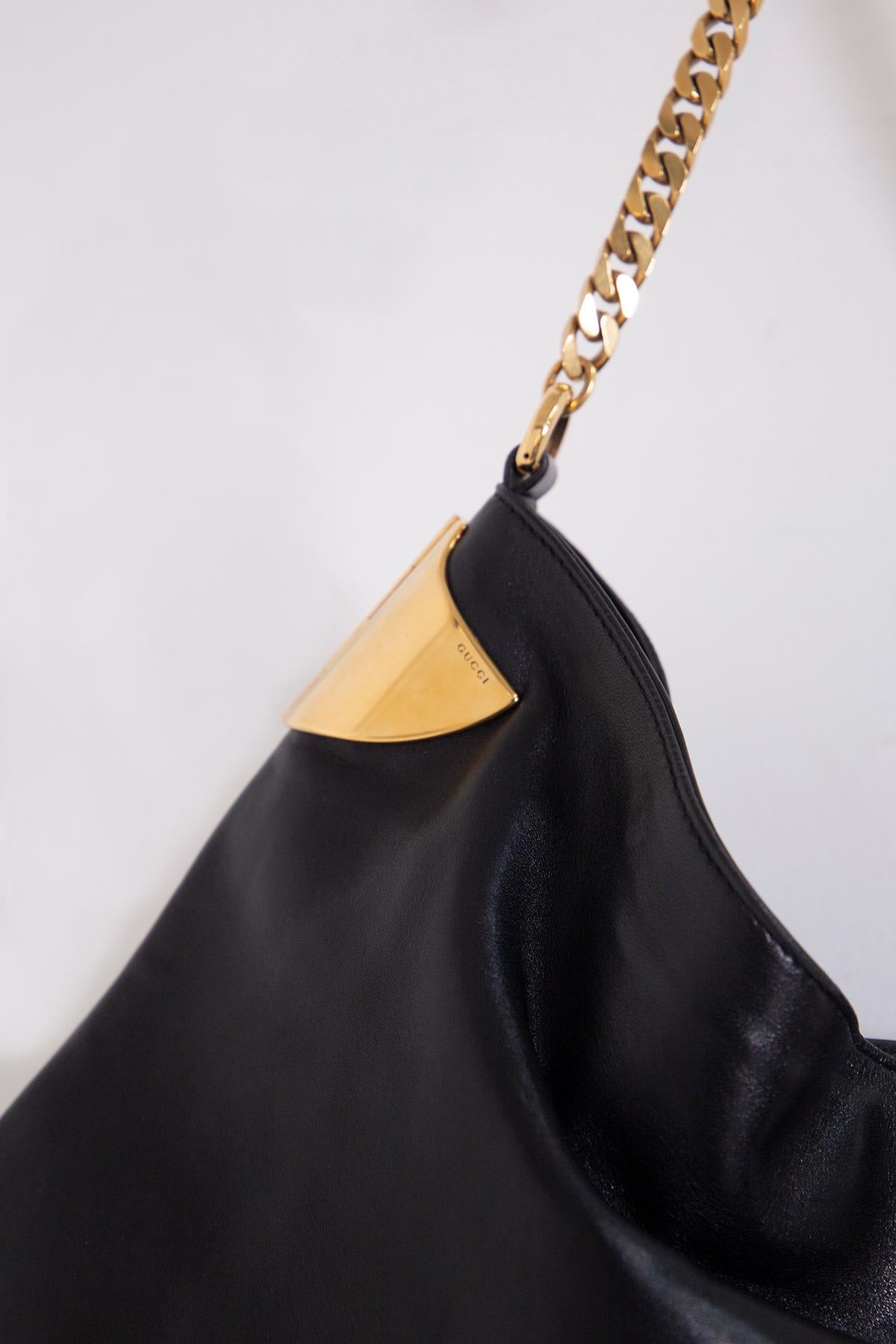 Original and wonderful Gucci shoulder bag from the 1970 collection, made of very soft black leather, embellished with inserts, such as two plates on the sides, a chain shoulder strap and a tassel, in gold metal. On the chain there is a leather