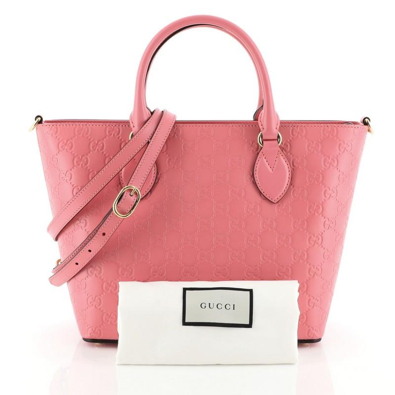 This Gucci Signature Convertible Tote Guccissima Leather Medium, crafted from pink guccissima leather, features dual rolled leather handles, protective base studs, and gold-tone hardware. Its zip closure opens to a neutral microfiber interior with