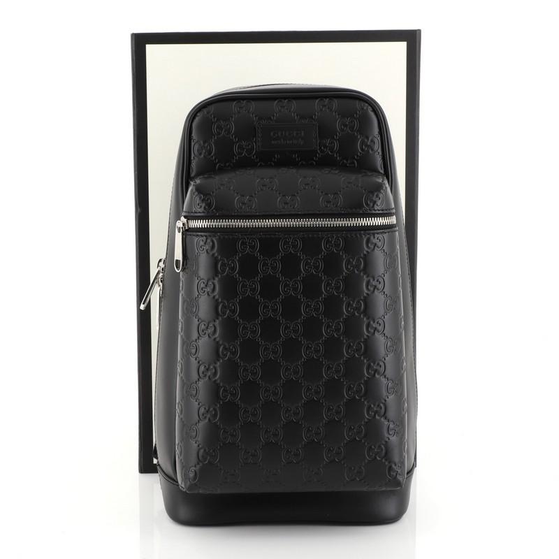 This Gucci Signature Slim Crossbody Bag Guccissima Leather Small, crafted in black guccissima leather, features textile shoulder strap, exterior front zip pocket, and silver-tone hardware. Its zip closure opens to a gray microfiber interior with