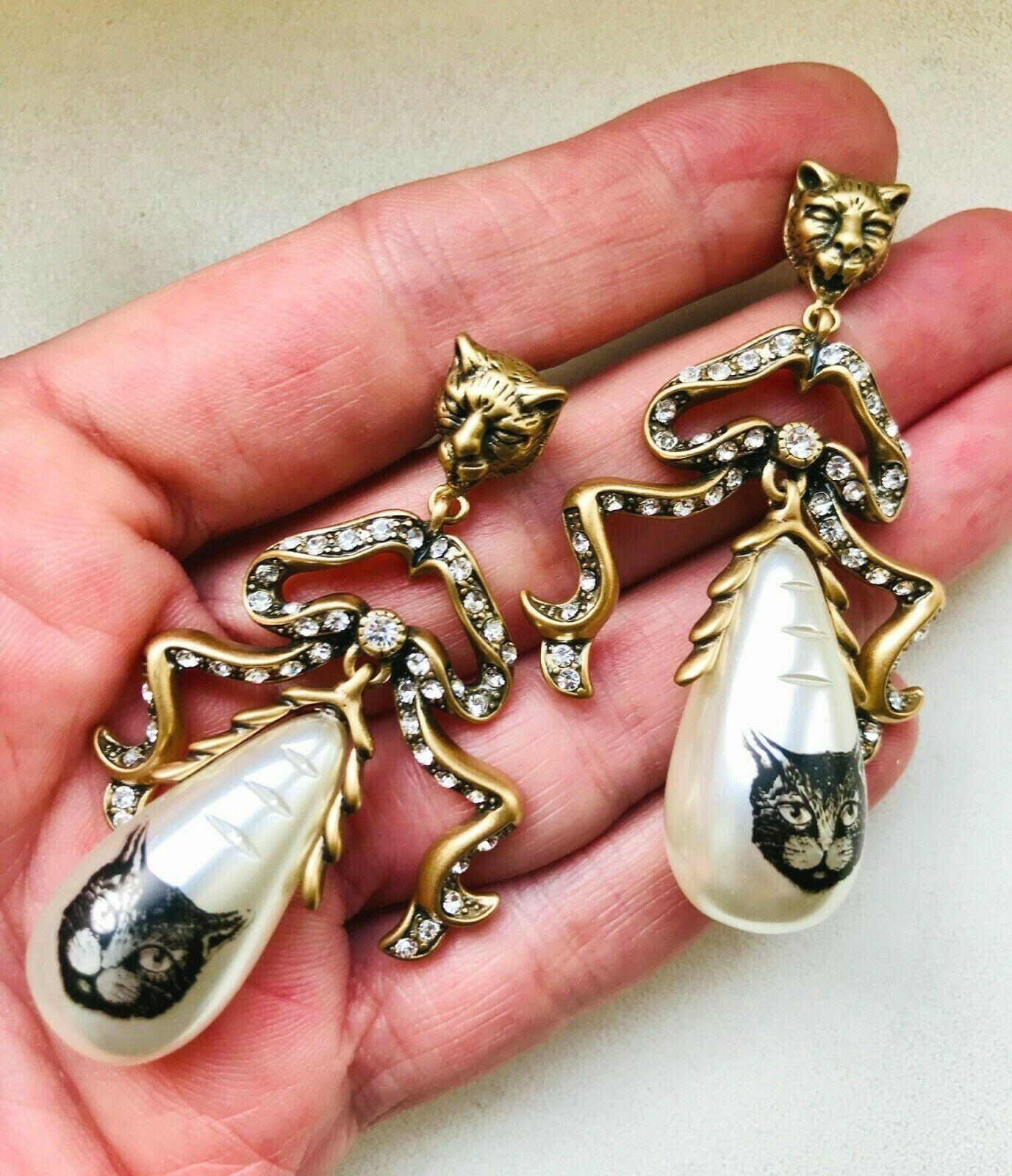 Fabulous Gucci Faux Pearl Dangle Earrings, Gold plated mountings; each earring has a Panther head, suspending a bow, enhanced with sparkling Faux Diamonds and a Teardrop Faux Pearl adorned with a cat’s head. Wow! Signed on reverse: GUCCI; Post