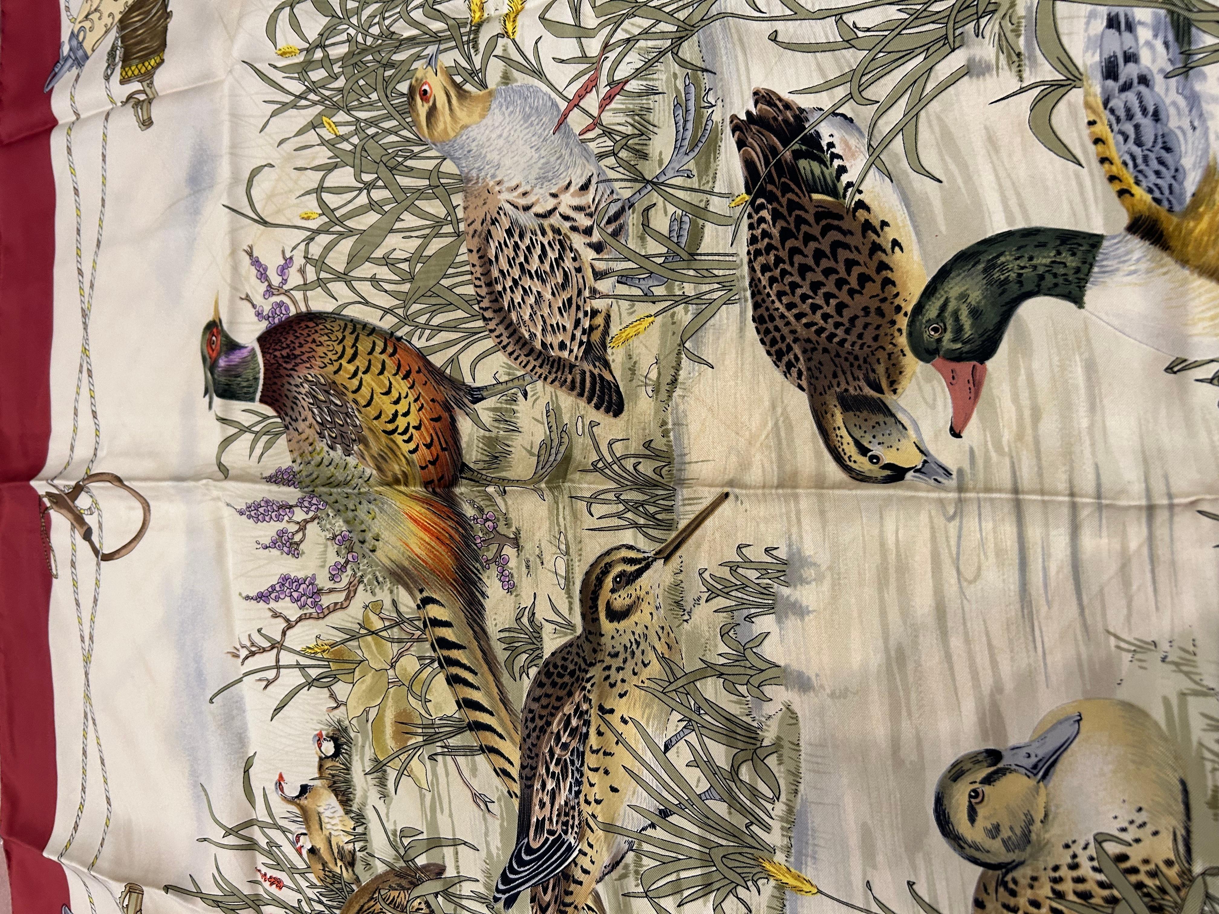 Sciarpa Gucci vintage anni '80 a quadri, colore beige e bordeaux, con uccelli raffigurati, piccole torri con monogramma Gucci agli angoli. Tessuto di seta. 

Misure: 86 x 86 cm