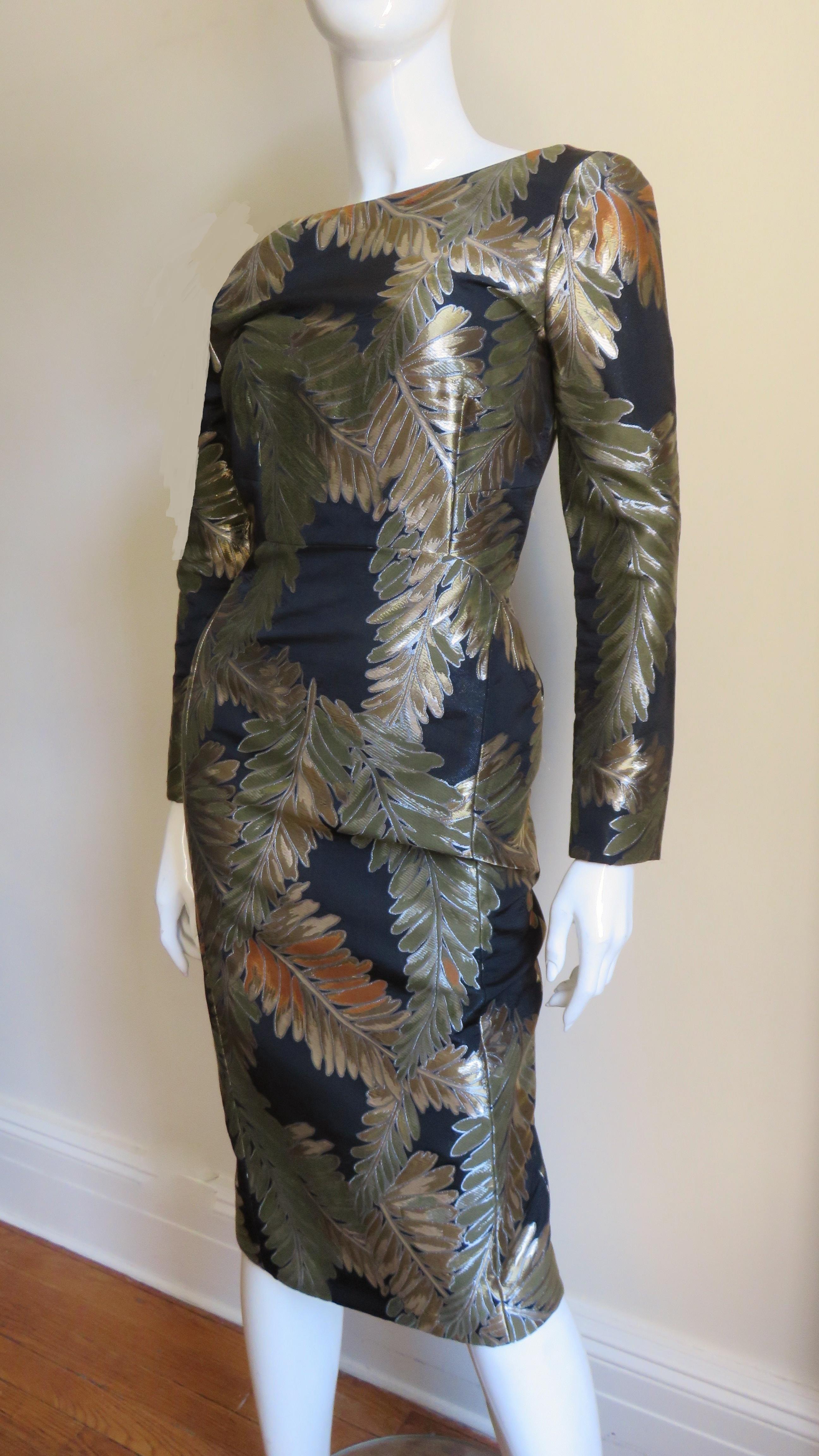 A fabulous silk dress from Gucci in a gold, rust and olive brocade fern pattern on a black background.  It is a semi fitted dress with long zipper cuff sleeves and fabulous flattering curved seaming at the waistline. The V back ends just above the