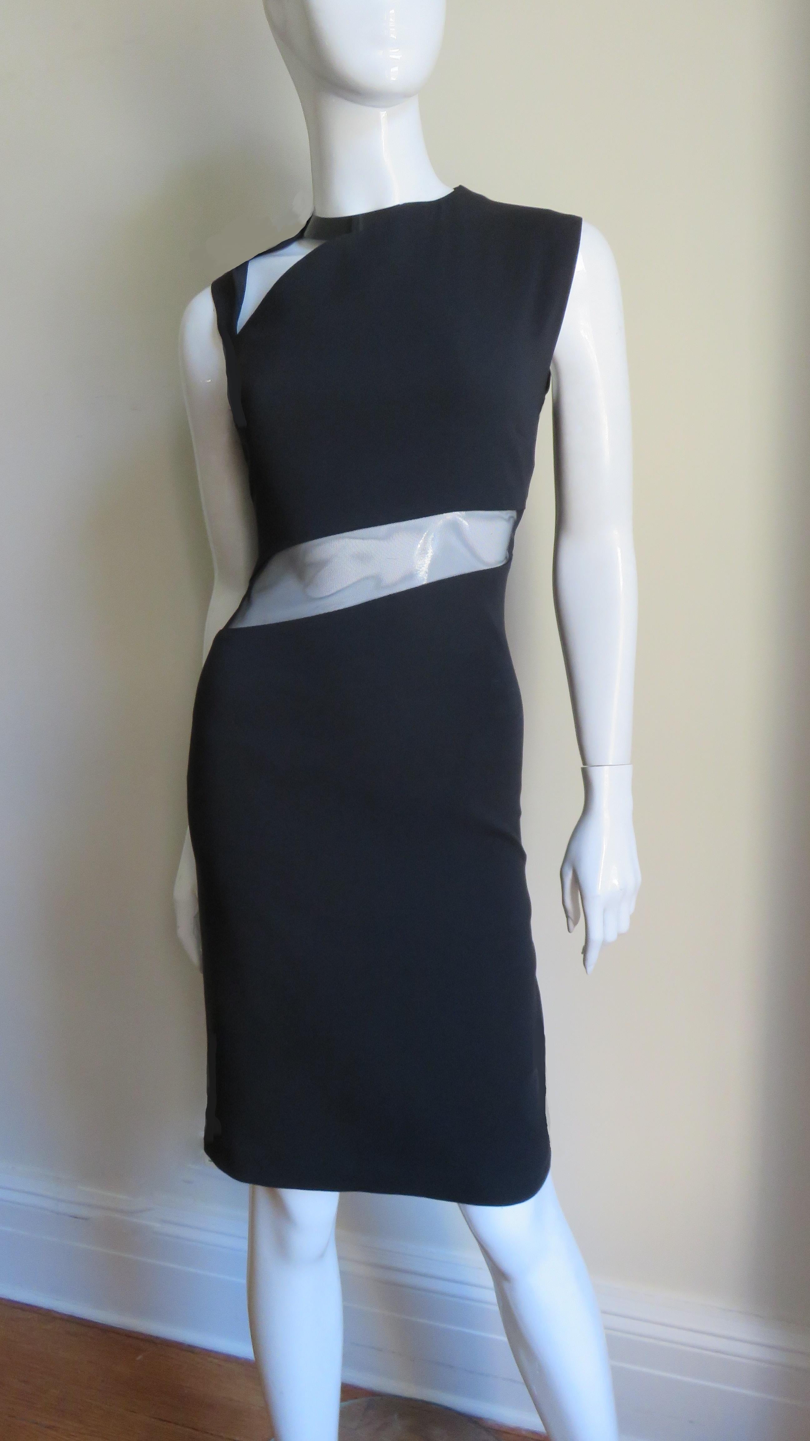 A fabulous black silk dress from Gucci.  It is semi fitted with a black metal collar with a cut out below it and another cut out diagonally across the front waist covered in black mesh.  The skirt is straight, there is a matching back invisible