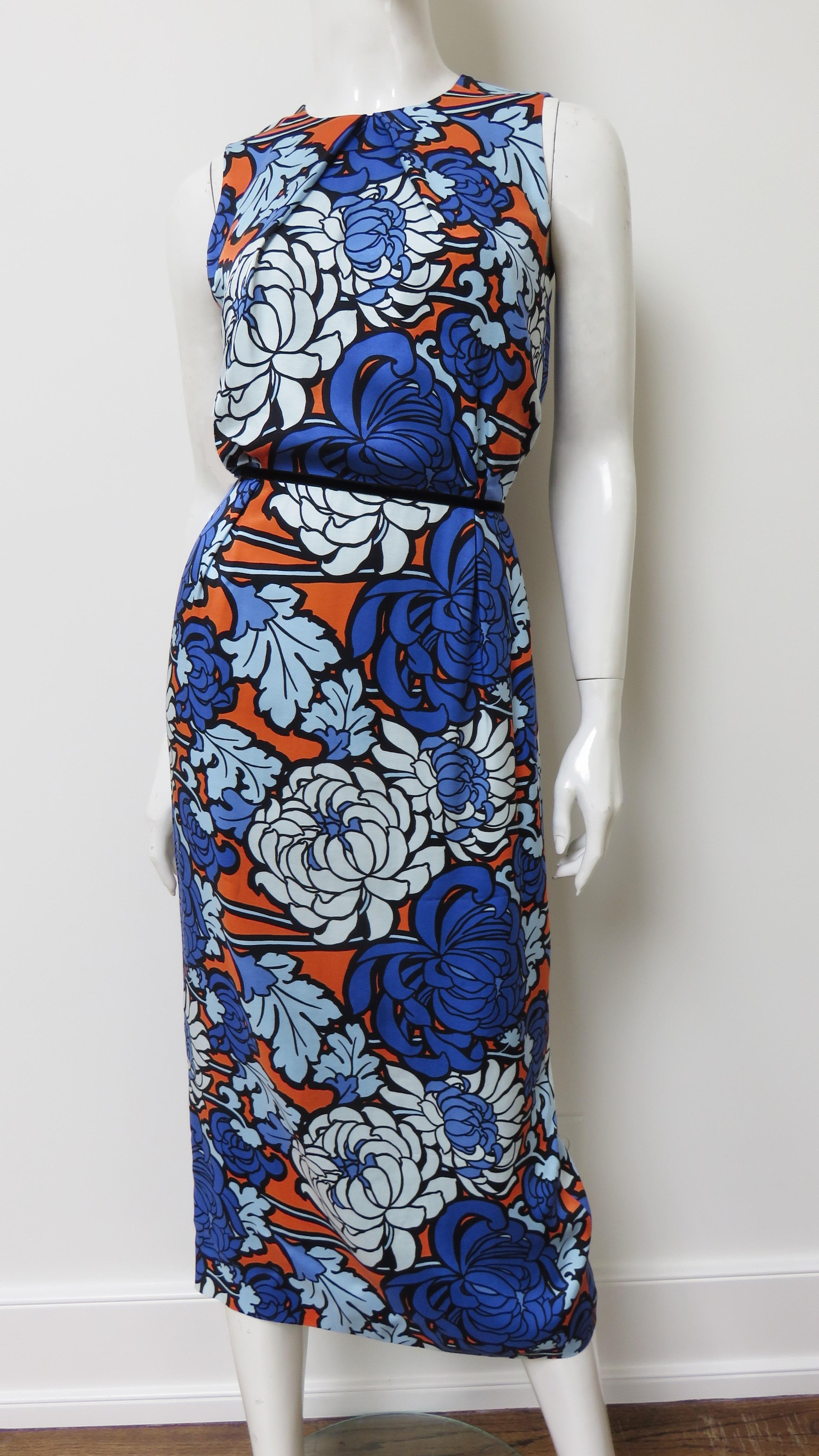 A fabulous chrysanthemum print silk dress in shades of blue and orange.  It is sleeveless with a crew neckline and a midi length straight skirt with a back kick pleat. The dress is fully lined in silk and has back zipper.
Fits sizes Small,