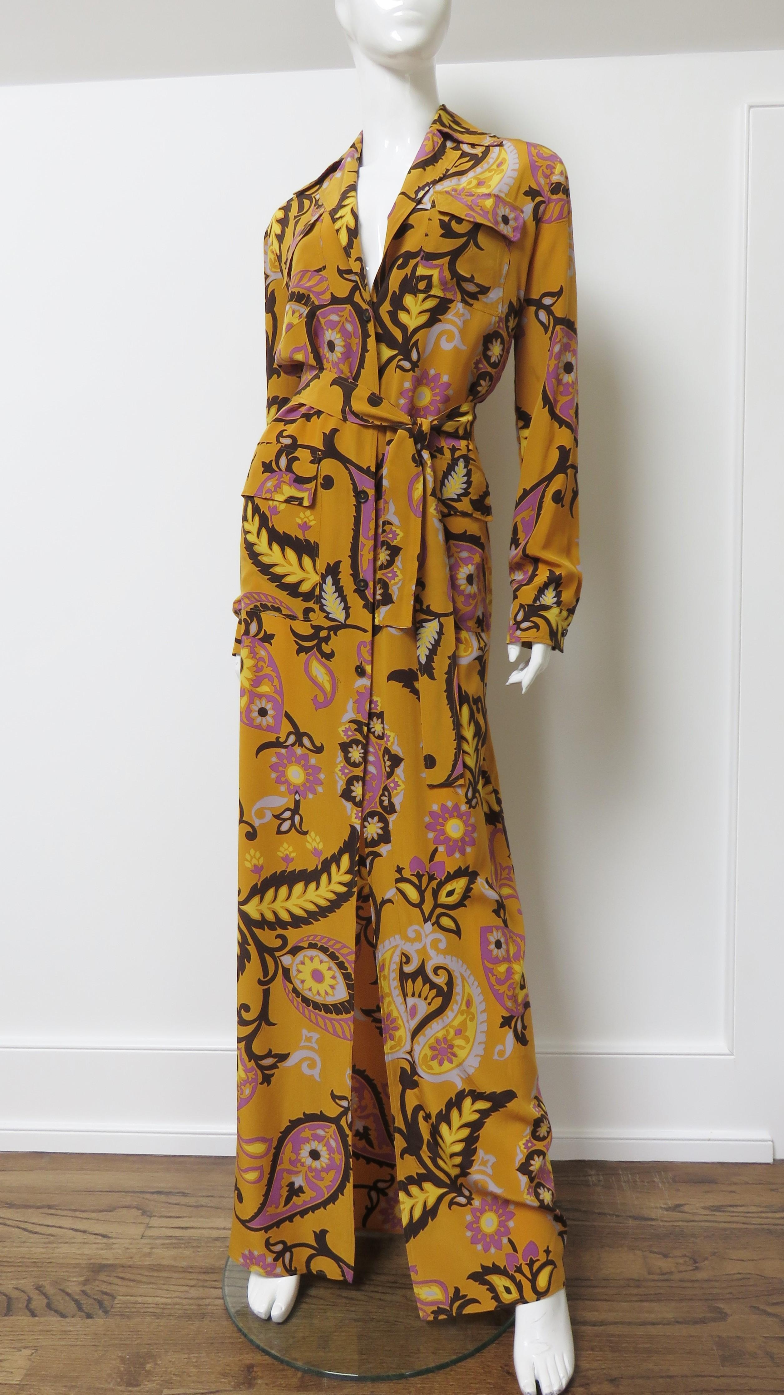 A fabulous silk maxi dress from Gucci in a marigold yellow, black, and purple abstract print.  It is shirtwaist style, floor length with a lapel collar, long sleeves, 4 front flap patch pockets- 2 on the chest- 2 at the hips, and a matching tie