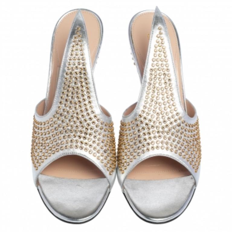 La bella struttura, la vestibilità comoda e il fascino accattivante definiscono queste mules Fedra di Gucci. Le mules in pelle argentata hanno un design open-toe sollevato da un tacco di 10 cm con borchie e la tomaia, tagliata a punta, è ricoperta