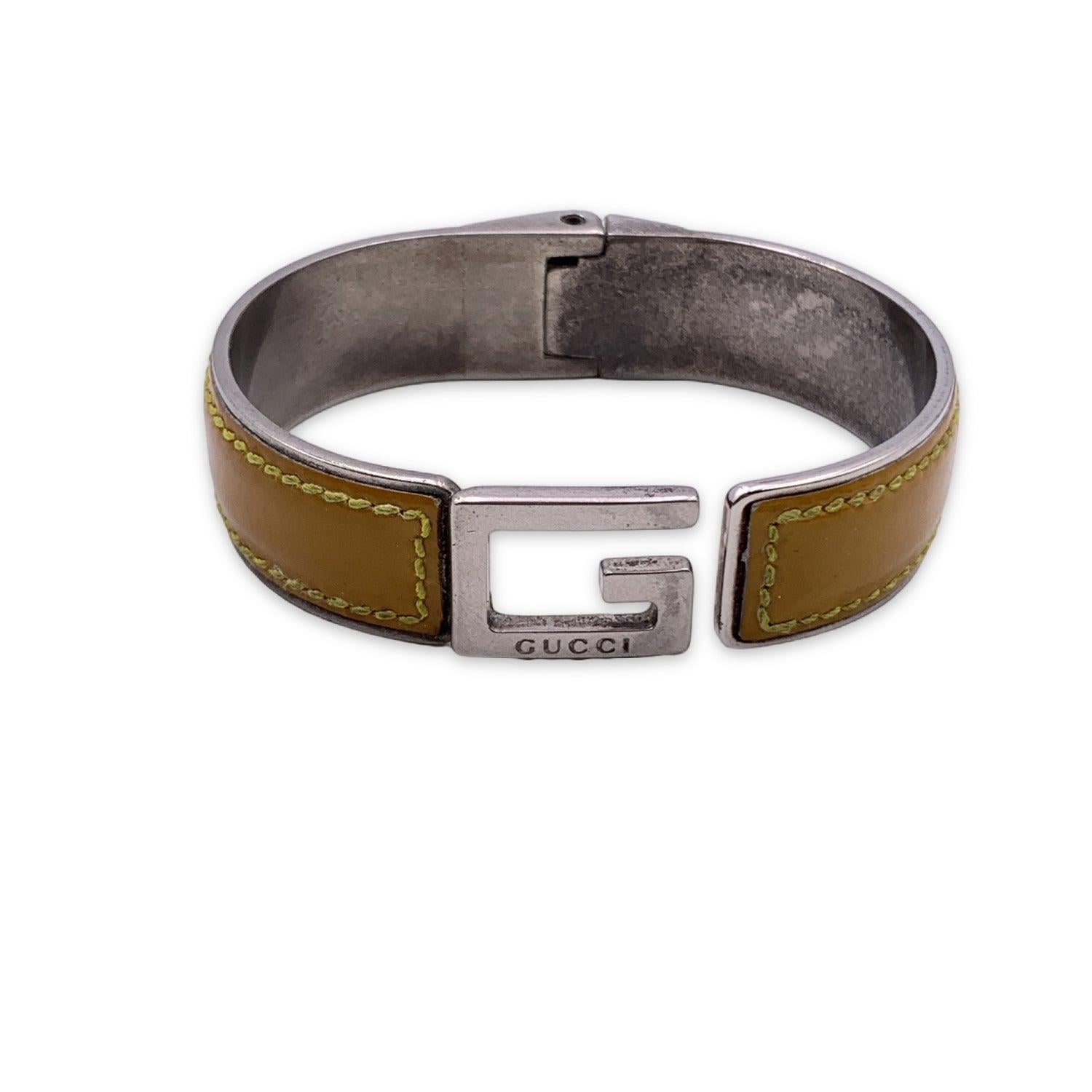 Silver tone metal bangle bracelet with G logo by GUCCI. Yellow patent leather. Spring hinge for easy wearing. Made in Italy. Max width (internally): 2.5 inches - 6.5 cm. Internal circumference: 7 inches - 17.7 cm Condition B - VERY GOOD Gently used.