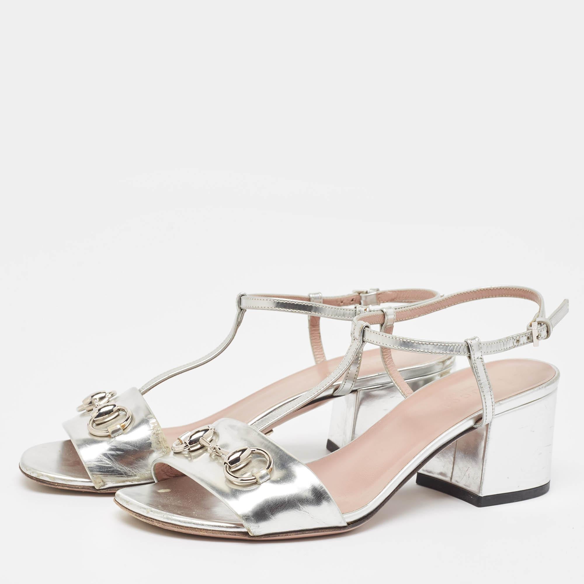 Meet these elegant Gucci T-Strap Sandals! Crafted in metallic silver leather, they feature open toes and silver-tone Horsebit detailing at the vamps. They have T-straps extending to the ankle straps with side buckle fastenings. The insoles are