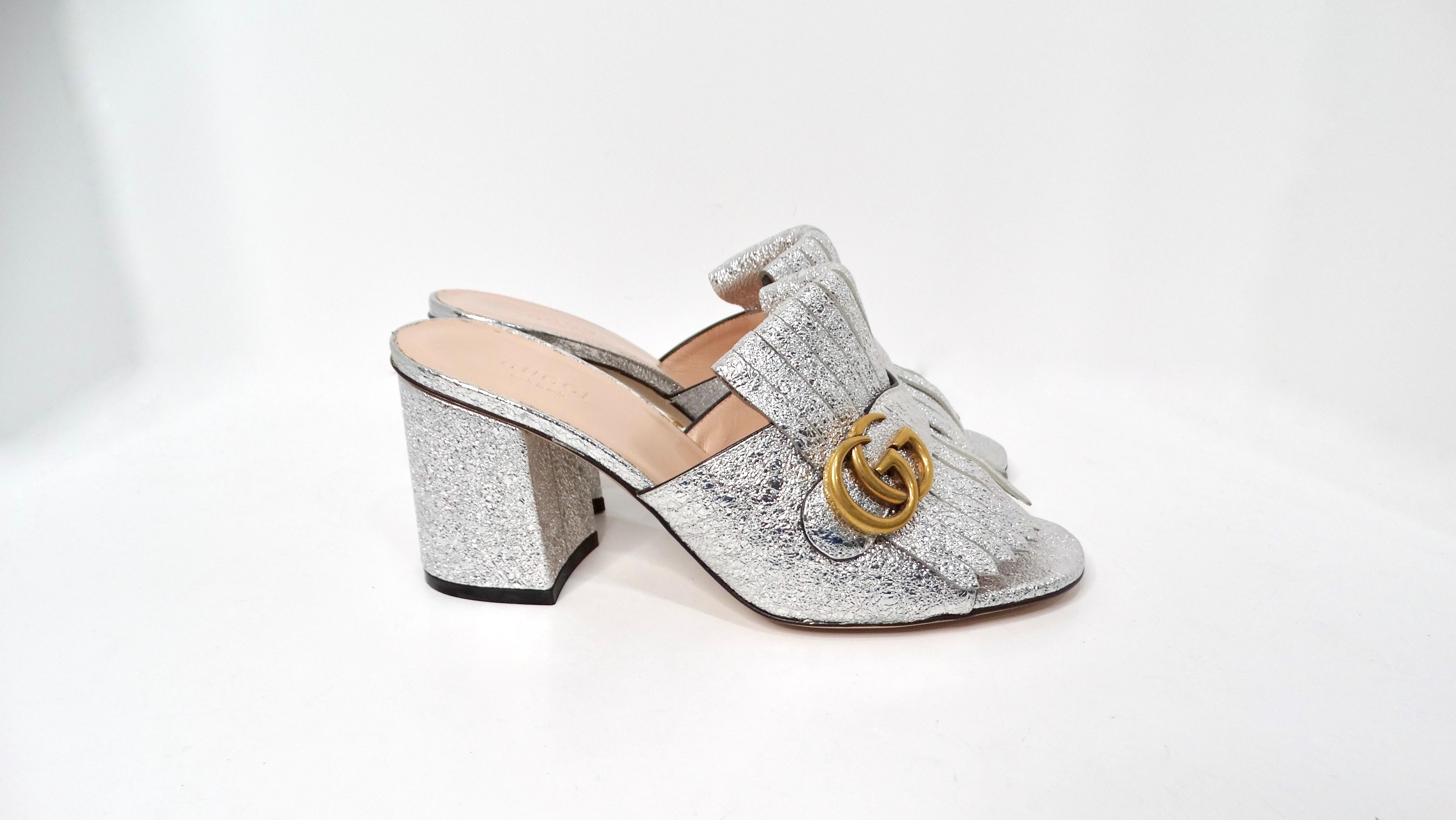 The Gucci Silver Metallic Marmont Fringe Mule Sandals are the epitome of luxurious statement footwear, combining modern design with classic elegance. Crafted from eye-catching silver foil metallic leather, these mules feature playful fringe