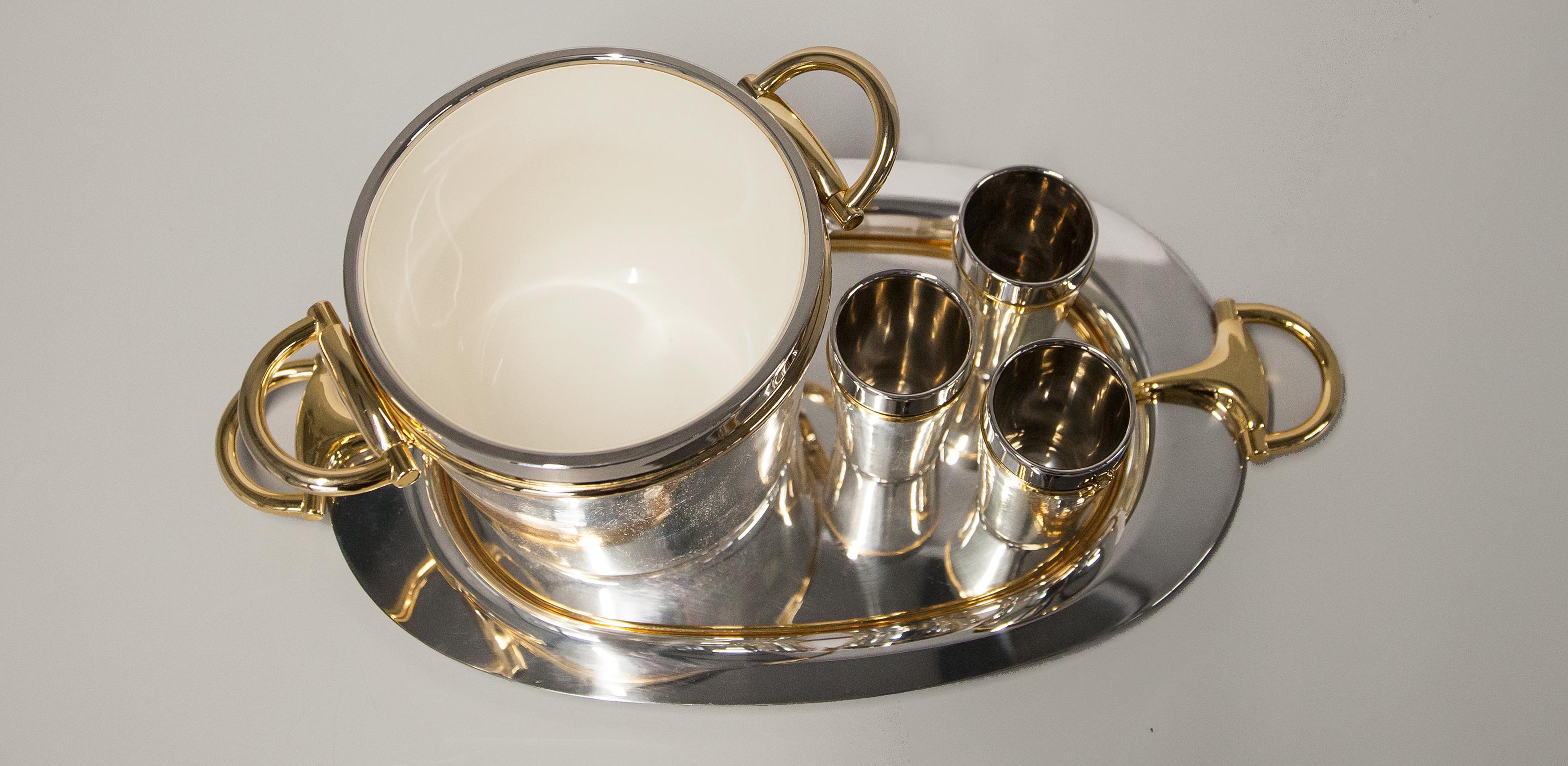 Very rare and special vintage Gucci bar set consisting of a monumental oval tray, three mugs and an elegant large wine cooler. Everything made of silver and gold plated brass and designed in the typical Gucci stirrup design, and of course all pieces
