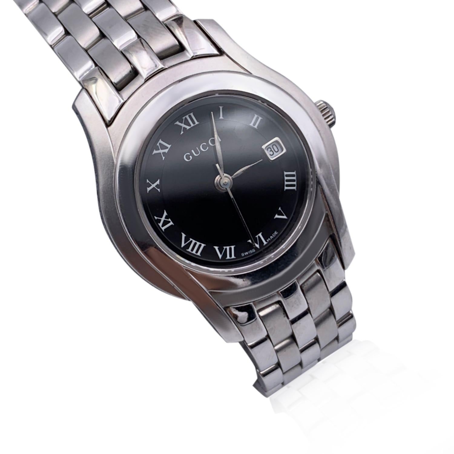 Gucci silver tone stainless steel wrist watch, mod. 5500 L. Black Dial. Date at 3 o'clock. Sapphire crystal. Swiss Made Quartz movement. Gucci written on face. Roman numbers. Gucci crest on the reverse of the case. Water Resistant to 3atm. Stainless