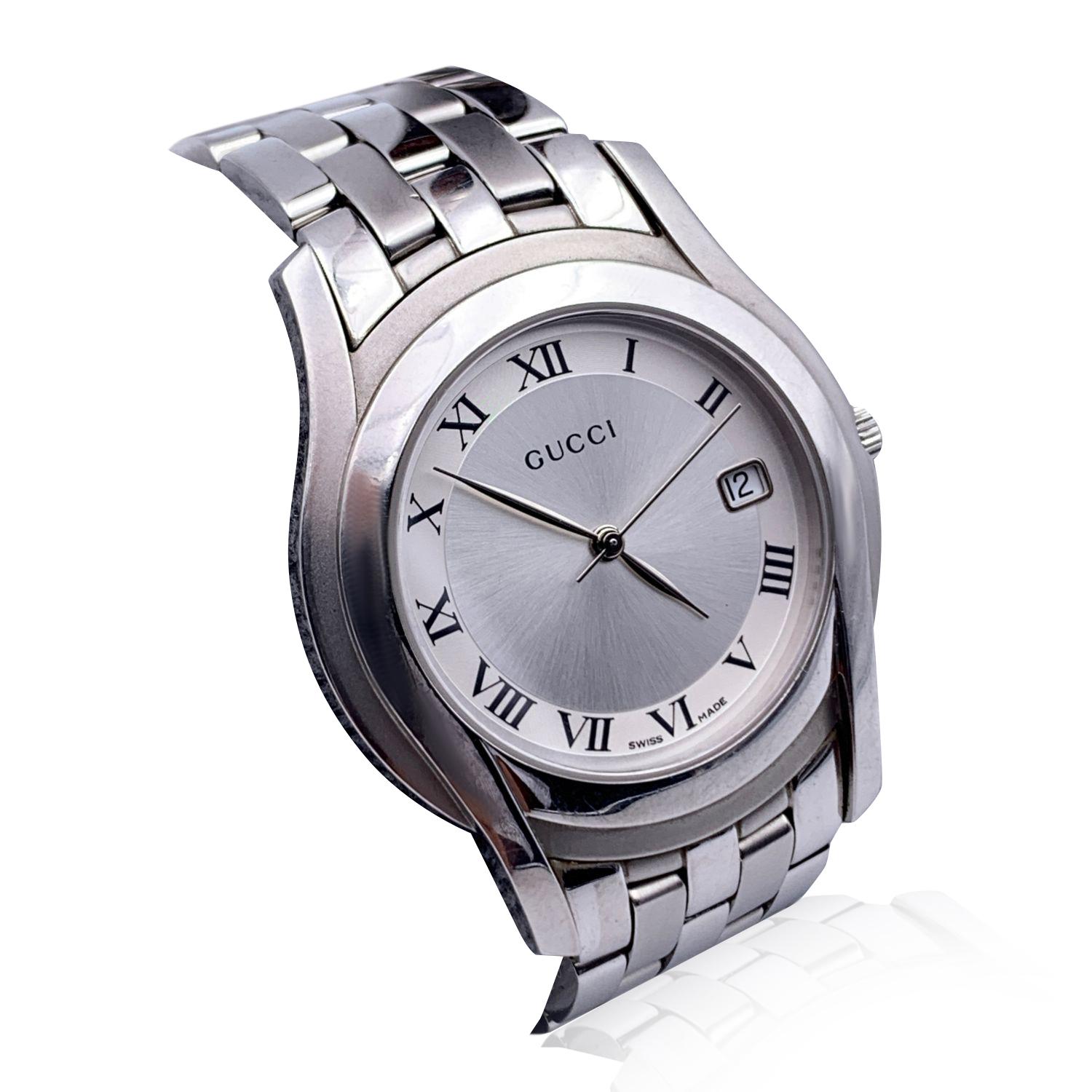 Gucci silver tone stainless steel wrist watch, mod. 5500 M. Silver Dial. Date at 3 o'clock. Sapphire crystal. Swiss Made Quartz movement. Gucci written on face. Roman numbers. Gucci crest on the reverse of the case. GUCCI logo engraved on the clasp.