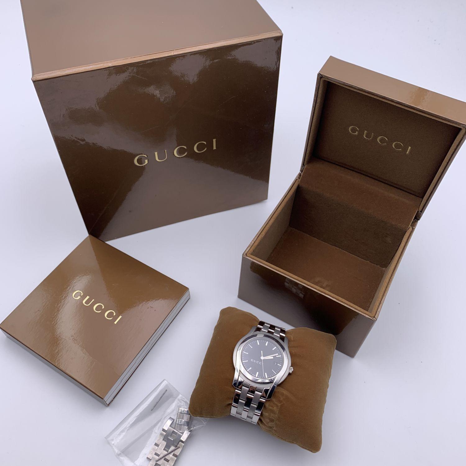 Gucci silver tone stainless steel wrist watch, mod. 5500 XL. Black Dial. Date at 3 o'clock. Sapphire crystal. Swiss Made Quartz movement. Gucci written on face. Roman numbers. Gucci crest on the reverse of the case. GUCCI logo engraved on the clasp.
