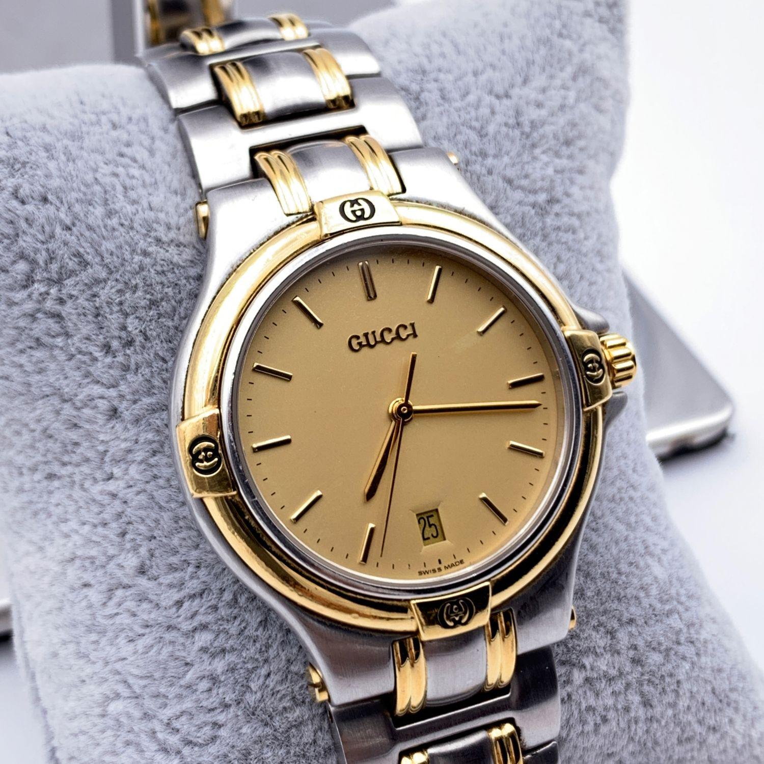 Gucci stainless steel wrist watch, mod. 9040 M. Stainless steel case with gold metal accents. Gold Dial. Date at 6 o'clock. Sapphire crystal. Swiss Made Quartz movement. Gucci written on face. Gucci crest on the reverse of the case. GG logo engraved