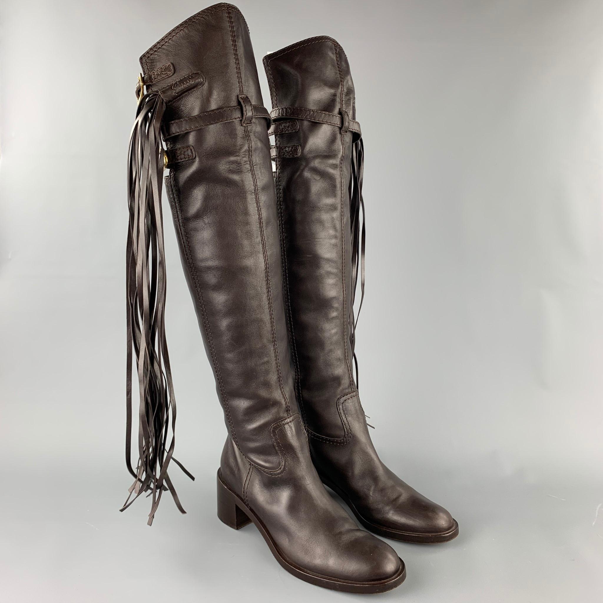 GUCCI boots comes in a brown leather featuring a over the knee style, buckle strap details on top, tassel design, pull on, and a wooden sole. Made in Italy.

Very Good Pre-Owned Condition.
Marked: EU 41
Original Retail Price: