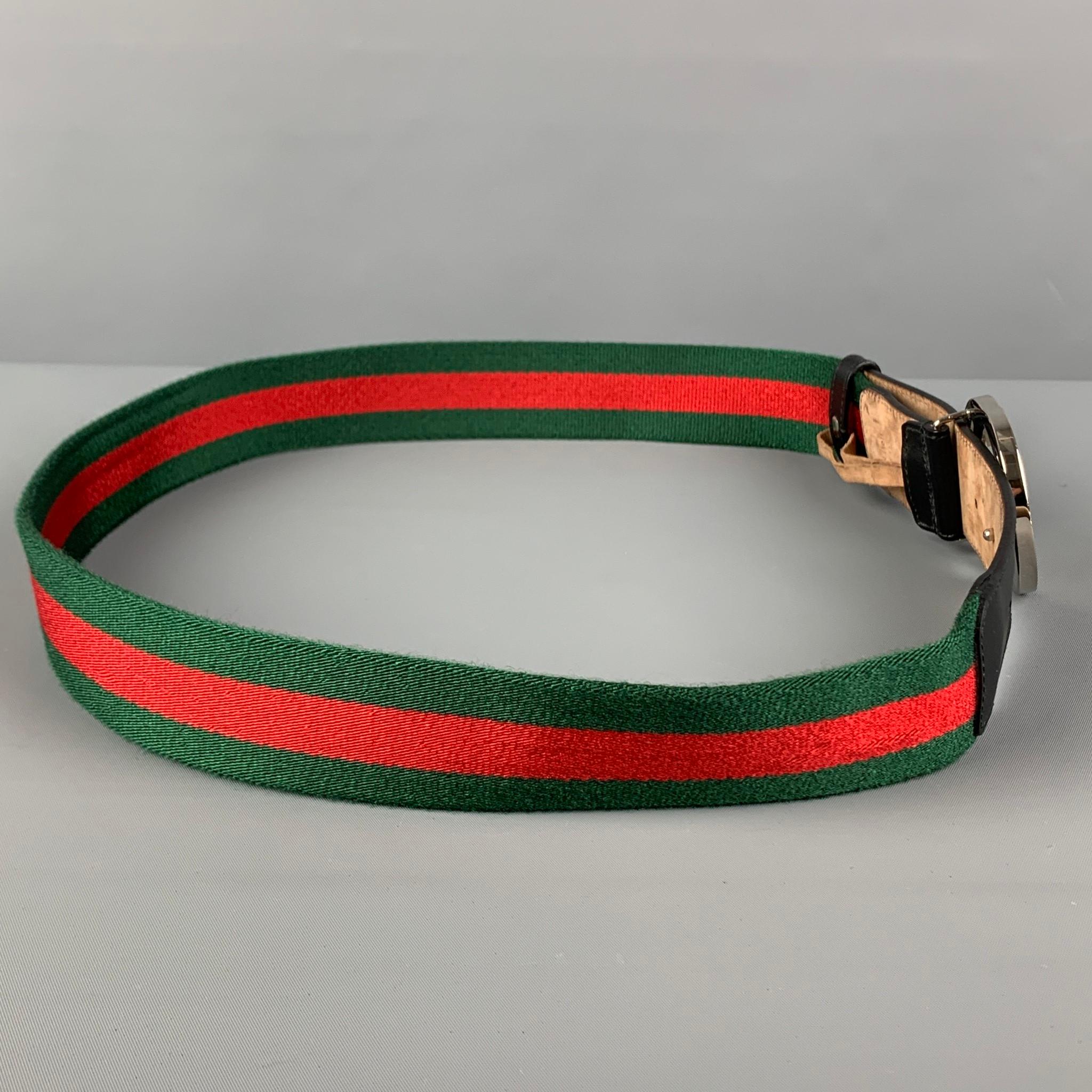 GUCCI belt comes in a green & red stripe material with a black leather trim featuring a silver tone 'GG' buckle closure. Made in Italy. 

Very Good Pre-Owned Condition.
Marked: 411924 H917N 95-38 525040

Length: 41.5 in.
Width: 1.5 in.
Fits: 35 in.