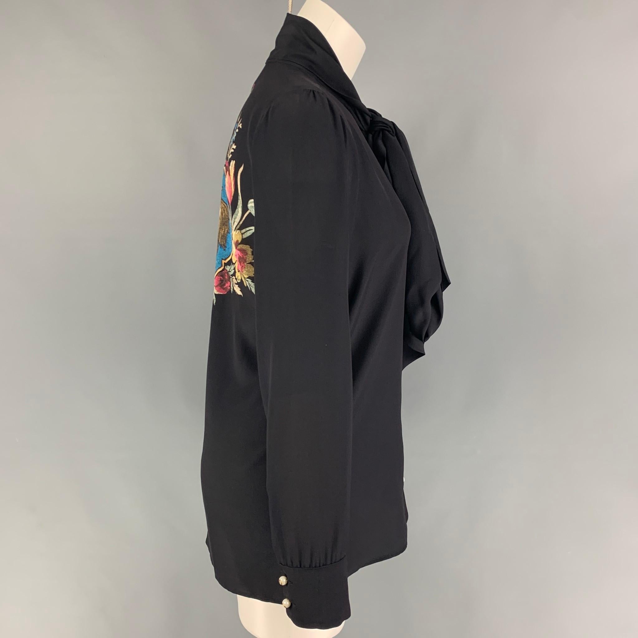 GUCCI blouse comes in a black silk featuring a front bow detail, back print design, and faux peal logo buttons. Made in Italy. 

Excellent Pre-Owned Condition.
Marked: 42

Measurements:

Shoulder: 14.5 in.
Bust: 38 in.
Sleeve: 24.5 in.
Length: 28