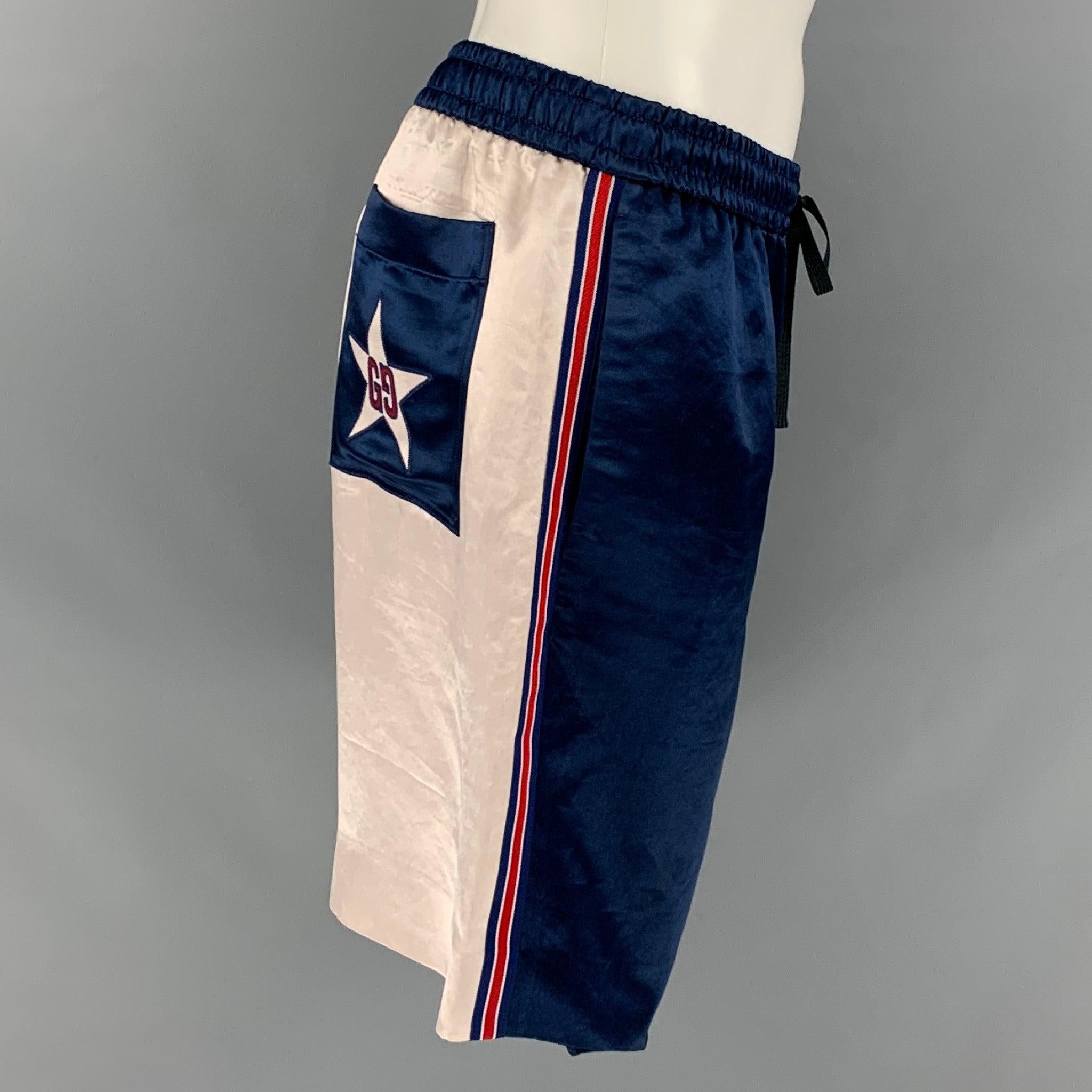 Gucci Acetate Athletic Shorts come in a Blue and Ivory Colorblock on either side of the shorts.
 Blue back pocket features a large star with GG.
 Slit Pockets and Drawstring.
 Made in Italy.Very Good Signs of Wear. 

Marked:   48 

Measurements: 
 