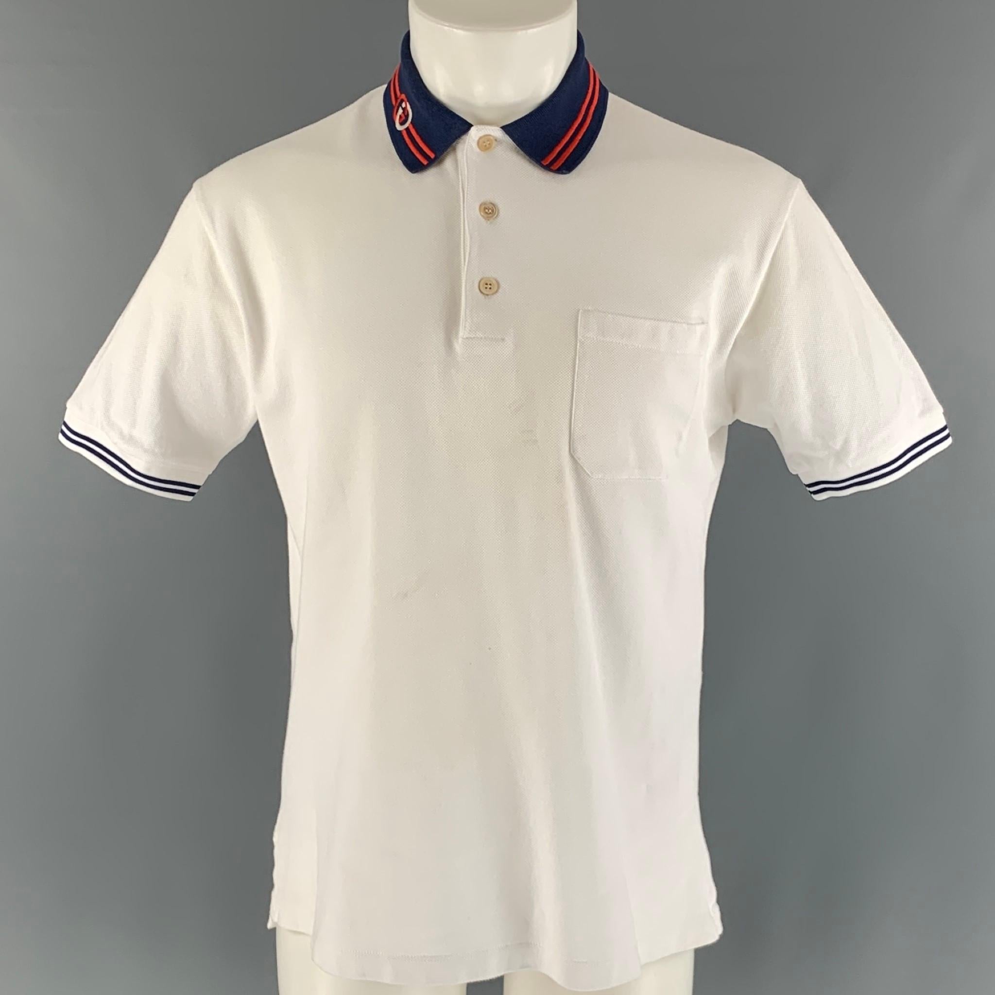 GUCCI polo comes in a white cotton piquet knit featuring a navy 'GG' collar, patch pocket, and a half buttoned closure. Made in Italy.

Very Good Pre-Owned Condition. Minor signs of wear.
Marked: M

Measurements:

Shoulder: 17.5 in.
Chest: 42