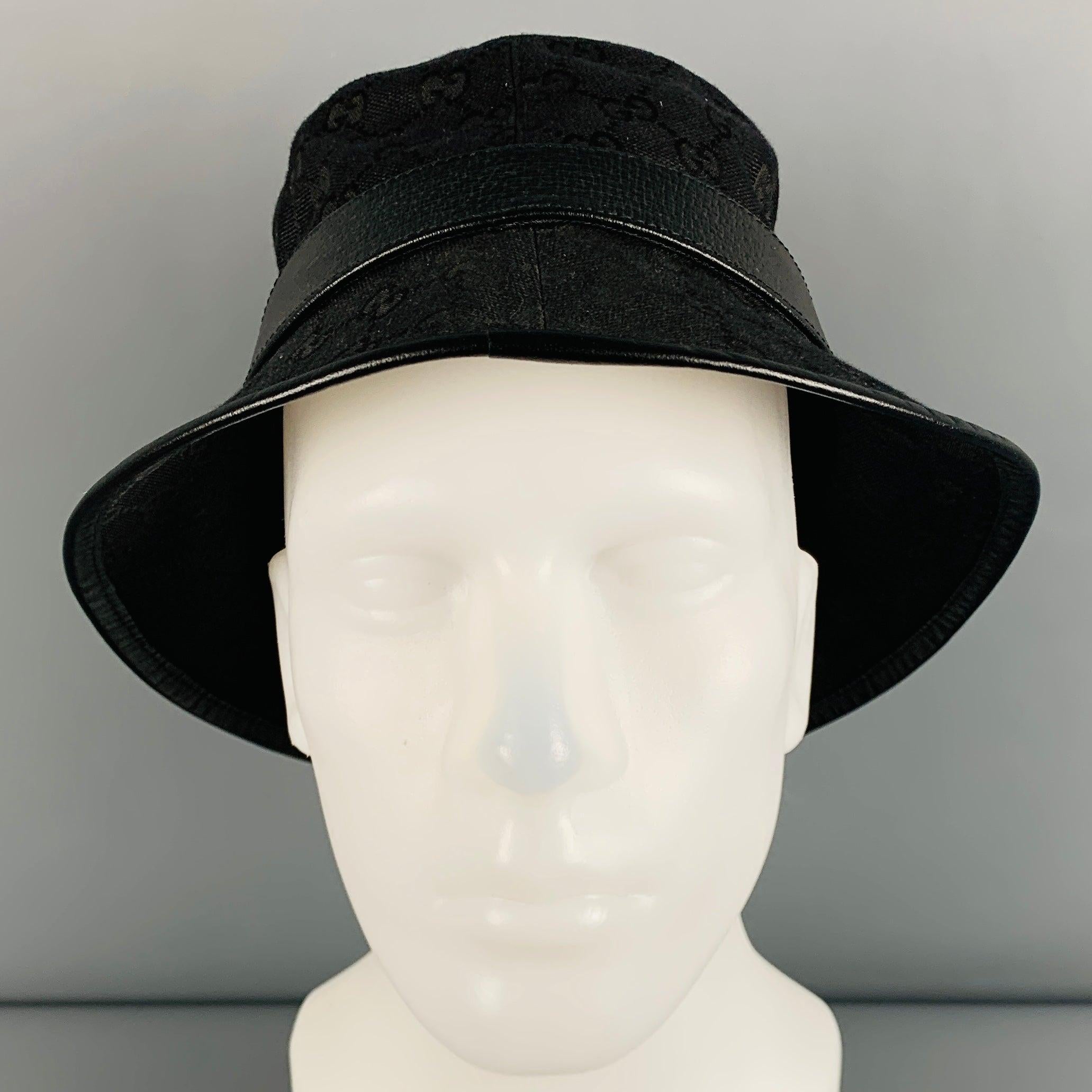 GUCCI hat in a
black polyester blend fabric featuring a bucket style, all over logo pattern, leather trim, and brass metal double GG detail.Very Good Pre-Owned Condition. Minor signs of wear. 

Marked:   S/57cm 

Measurements: 
  Opening: 22 inches