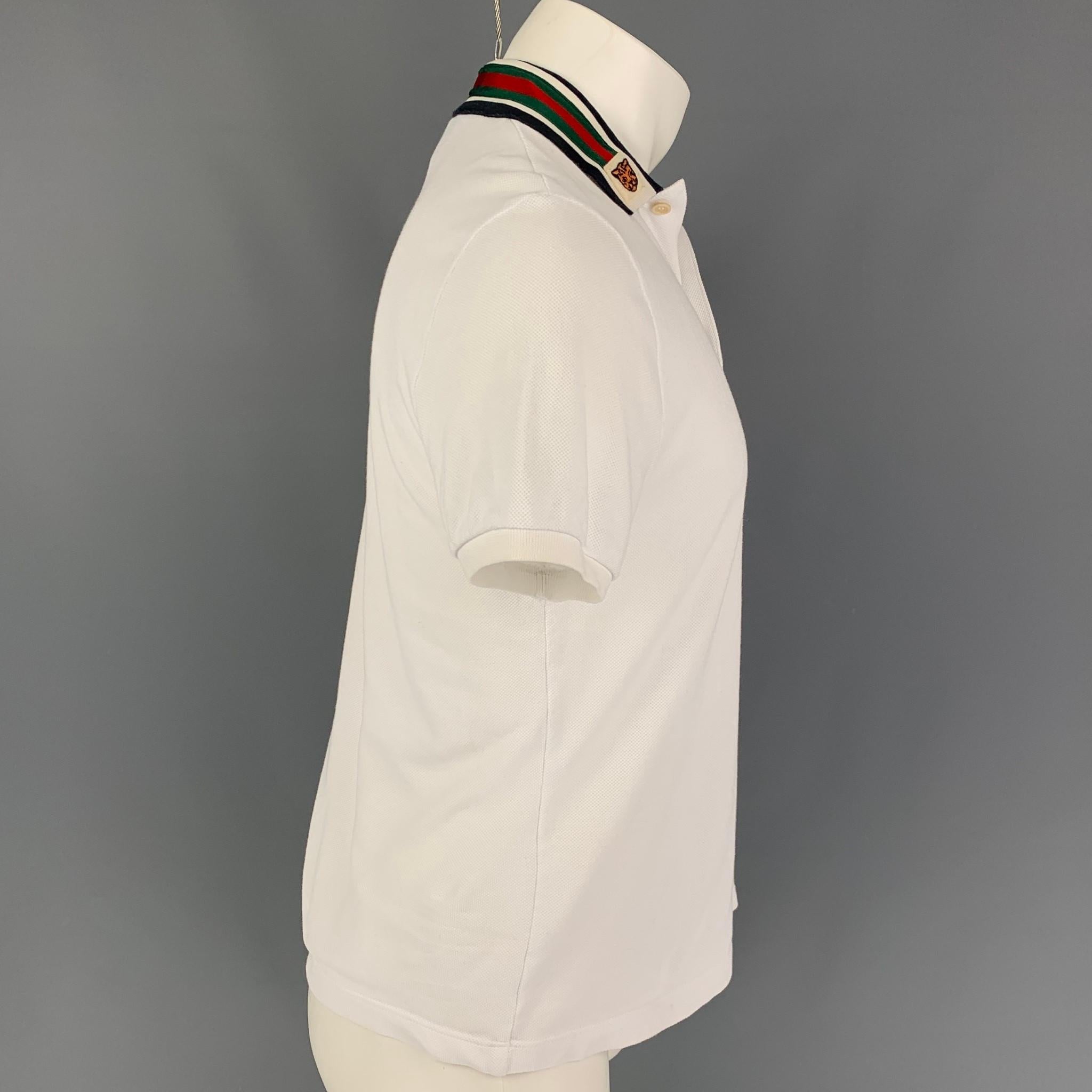GUCCI polo comes in  white cotton featuring a stripe collar, tiger patch applique, and a half buttoned closure. Made in Italy. 

Very Good Pre-Owned Condition.
Marked: S

Measurements:

Shoulder: 18 in.
Chest: 38 in.
Sleeve: 9 in.
Length: 23.5 in. 