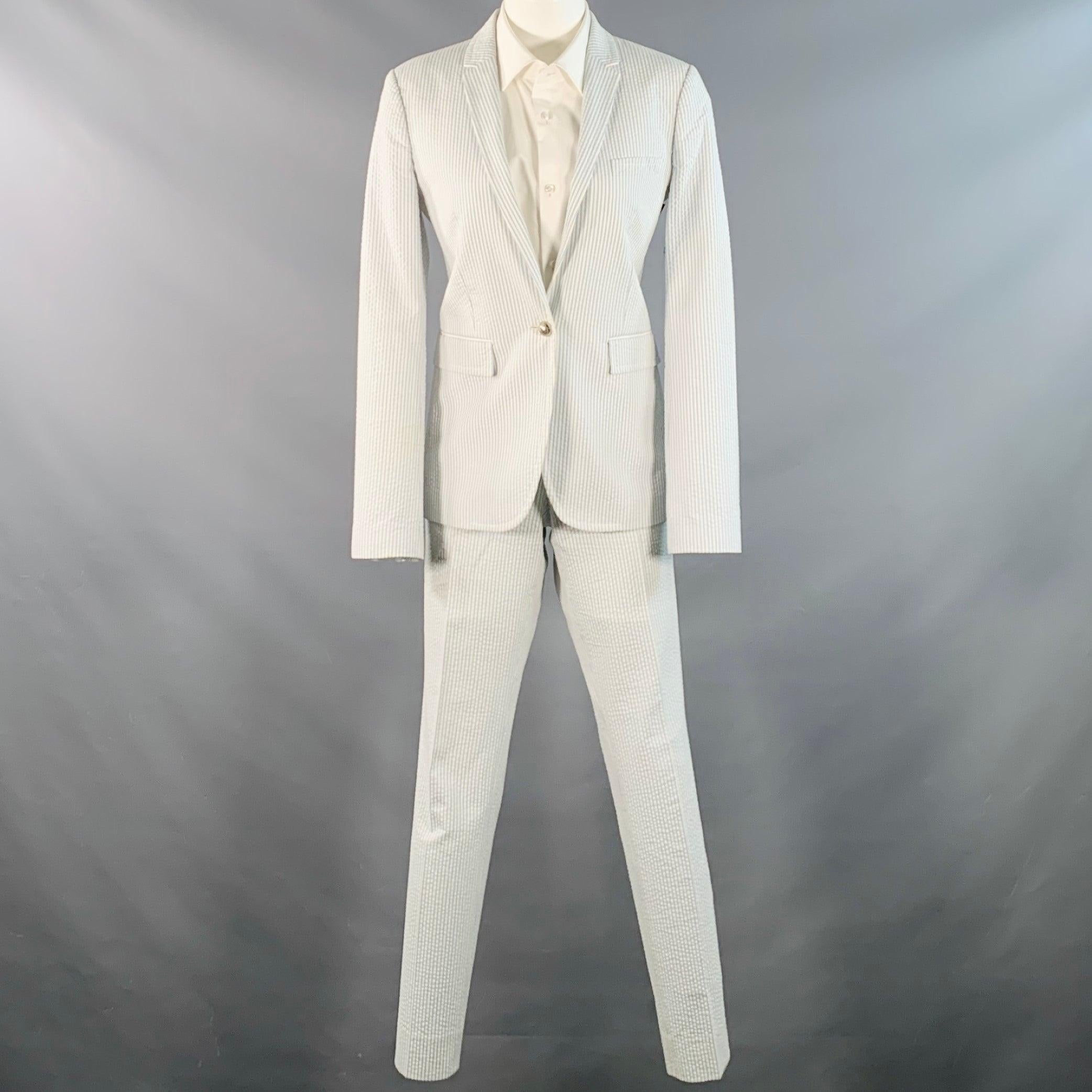 GUCCI-Anzug
in einem weiß-blau gestreiften Baumwoll-Seersucker mit Vollfutter und einem einreihigen, einknöpfigen Sportmantel mit gekerbtem Revers und einer passenden Hose mit flacher Front. Hergestellt in Italien, guter gebrauchter Zustand. Mäßige
