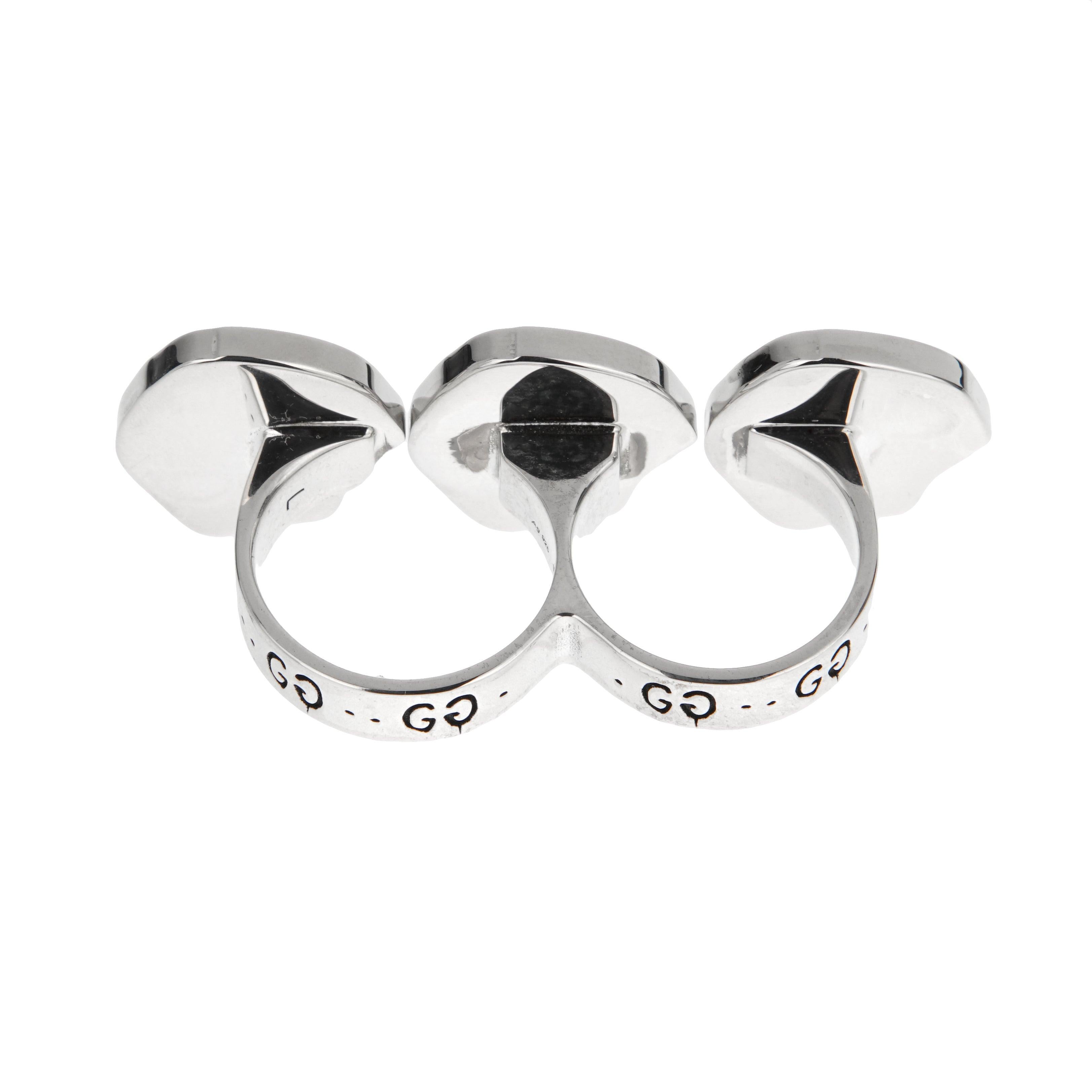 Anello a due dita in argento sterling di Gucci, scolpito in argento sterling brillante. Presenta tre motivi a teschio stilizzati, ognuno dei quali è ornato dall'iconico emblema 
