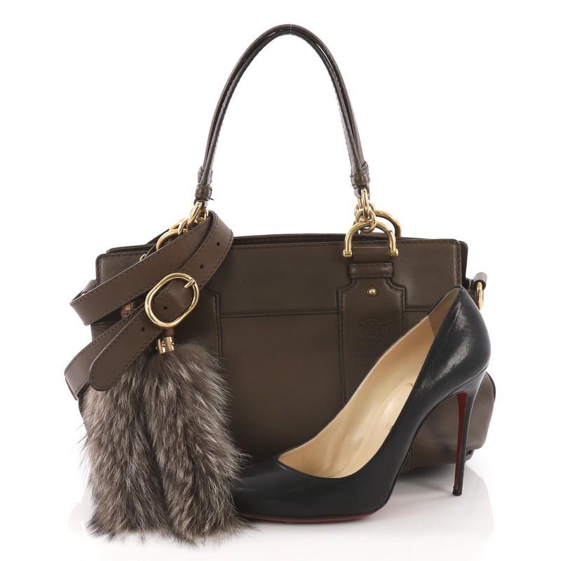 This Gucci Smilla Tote Leather Small, crafted in brown leather, features dual flat leather handles, raccoon tassels with bamboo knobs, and gold-tone hardware. Its magnetic snap closure opens to a beige fabric interior with zip and slip pockets.