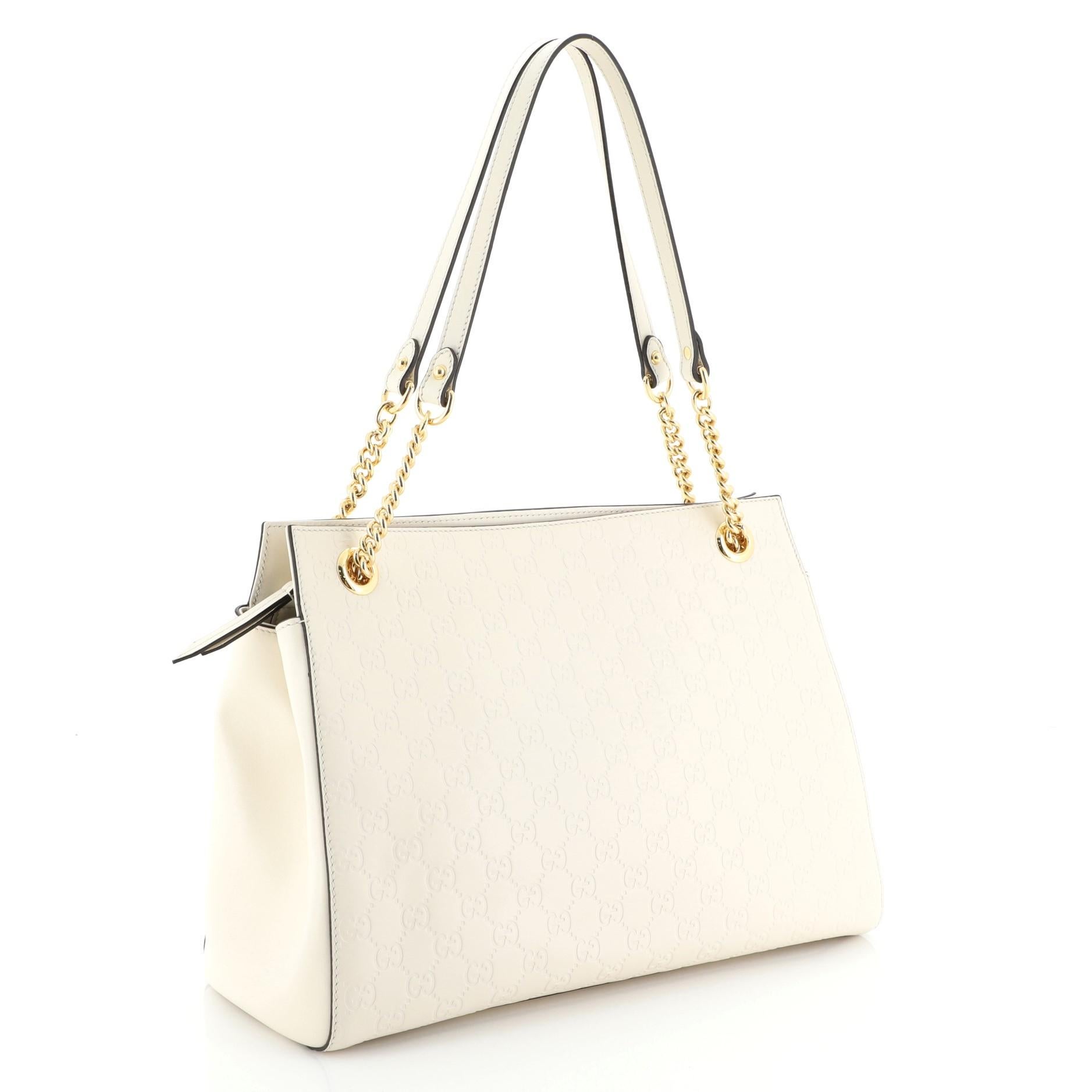 This Gucci Soft Signature Shoulder Bag Guccissima Leather Large, crafted from white guccissima leather, features chain-link shoulder straps with leather pads and gold-tone hardware. Its zip closure opens to a neutral microfiber interior with side