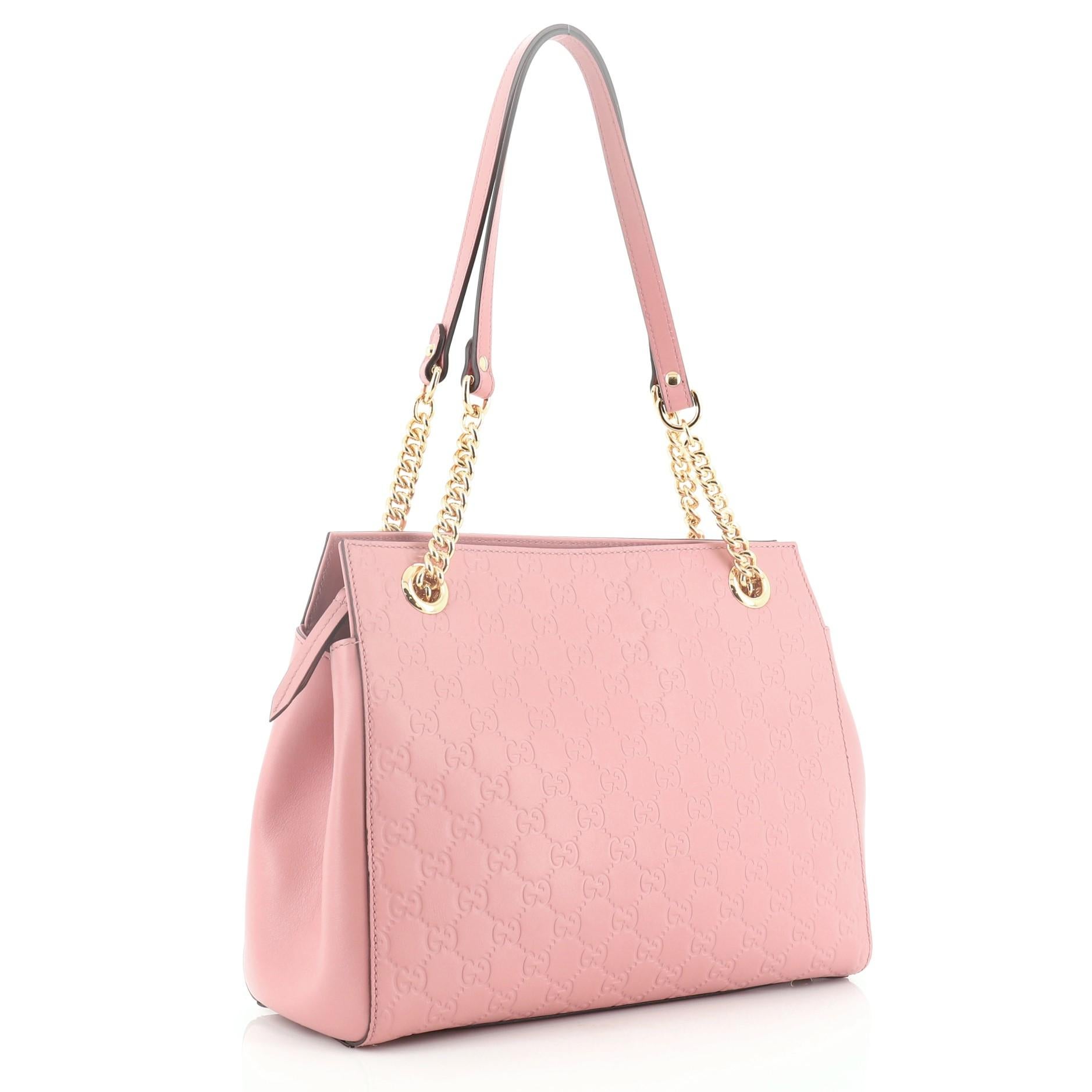 This Gucci Soft Signature Shoulder Bag Guccissima Leather Medium, crafted from pink guccissima leather, features dual chain-link shoulder straps with leather pads and gold-tone hardware. Its zip closure opens to a neutral microfiber interior with