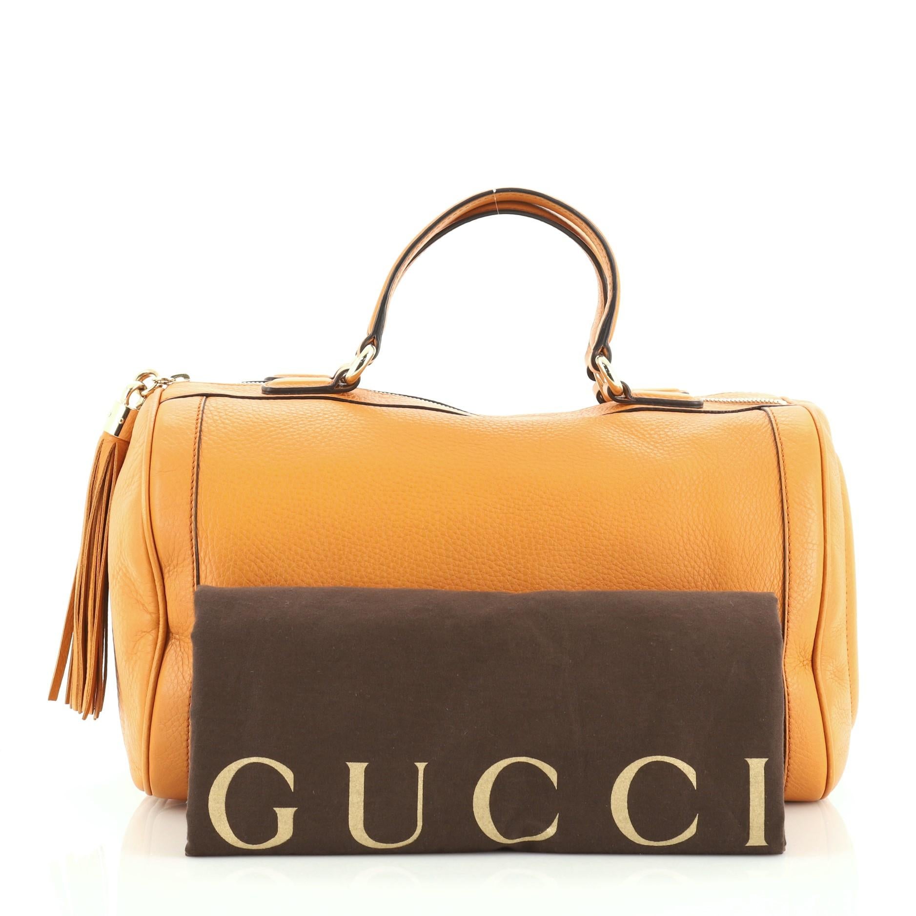This Gucci Soho Boston Bag Leather, crafted in orange leather, features dual flat handles, tassel zipper pull accent, stitched GG logo at the side, protective base studs and gold-tone hardware. Its zip closure opens to a neutral fabric interior with
