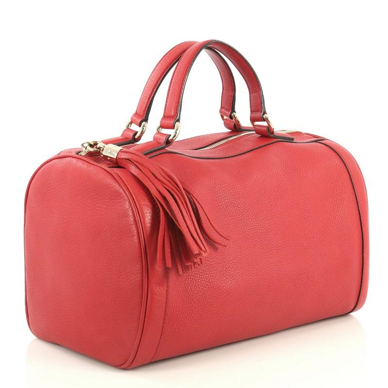 This Gucci Soho Boston Bag Leather, crafted in red leather, features dual flat handles, tassel zipper pull accent, stitched GG logo at the side, protective base studs and gold-tone hardware. Its zip closure opens to a neutral fabric interior with