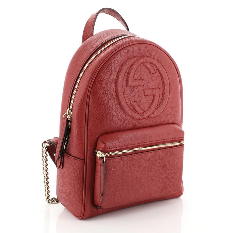 This Gucci Soho Chain Backpack Leather, crafted in red leather, features a top leather handle, chain link strap, exterior front zip pocket, and gold-tone hardware. Its zip closure opens to a neutral fabric interior with slip pockets. 

Estimated