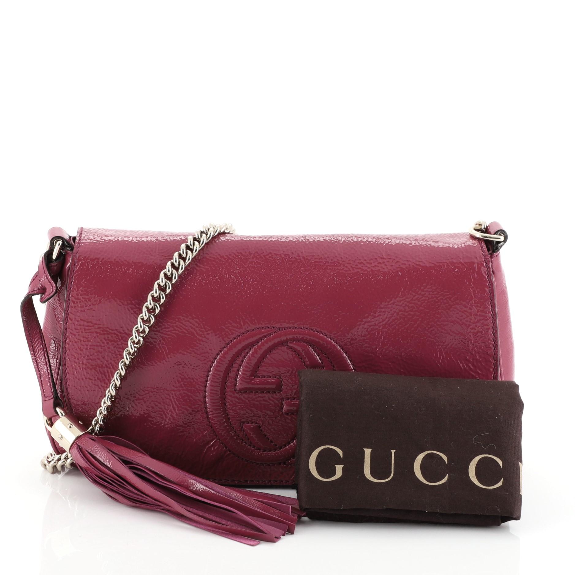 This Gucci Soho Chain Crossbody Bag Patent Medium, crafted from pink leather, features a long chain strap, stitched interlocking GG logo on its flap, and gold-tone hardware. Its hidden magnetic snap closure opens to a neutral fabric interior with