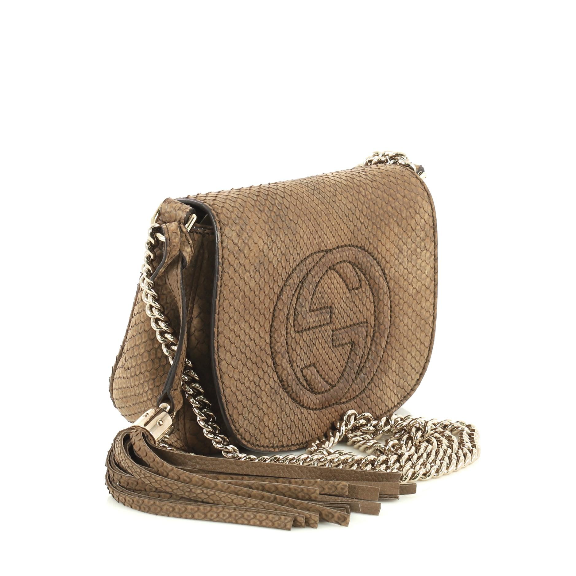 This Gucci Soho Chain Crossbody Bag Python Small, crafted from genuine brown python, features chain link strap, tassel accent, stitched interlocking GG logo, and gold-tone hardware. Its hidden magnetic snap closure opens to a neutral fabric interior