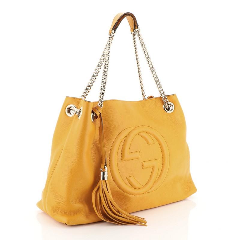 This Gucci Soho Chain Strap Shoulder Bag Leather Medium, crafted from orange leather, features an oversized interlocking GG logo, hanging tassel, chain straps and silver-tone hardware. Its snap button closure opens to a neutral fabric interior with