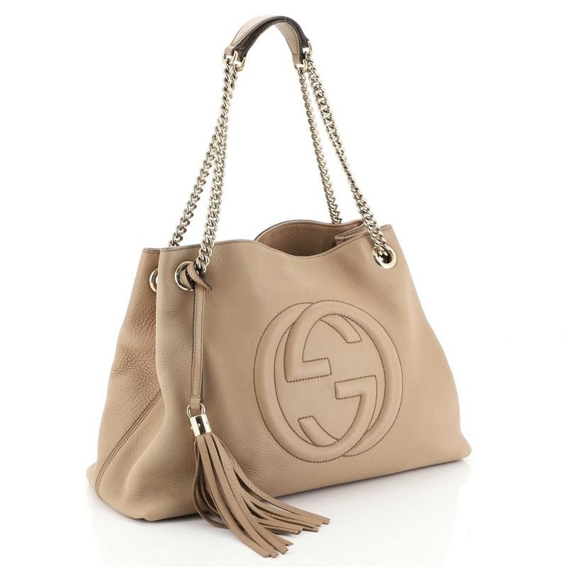 This Gucci Soho Chain Strap Shoulder Bag Leather Medium, crafted in neutral leather, features chain link straps with leather pads and gold-tone hardware. Its hook clasp closure opens to a neutral fabric interior with side zip and slip pockets.