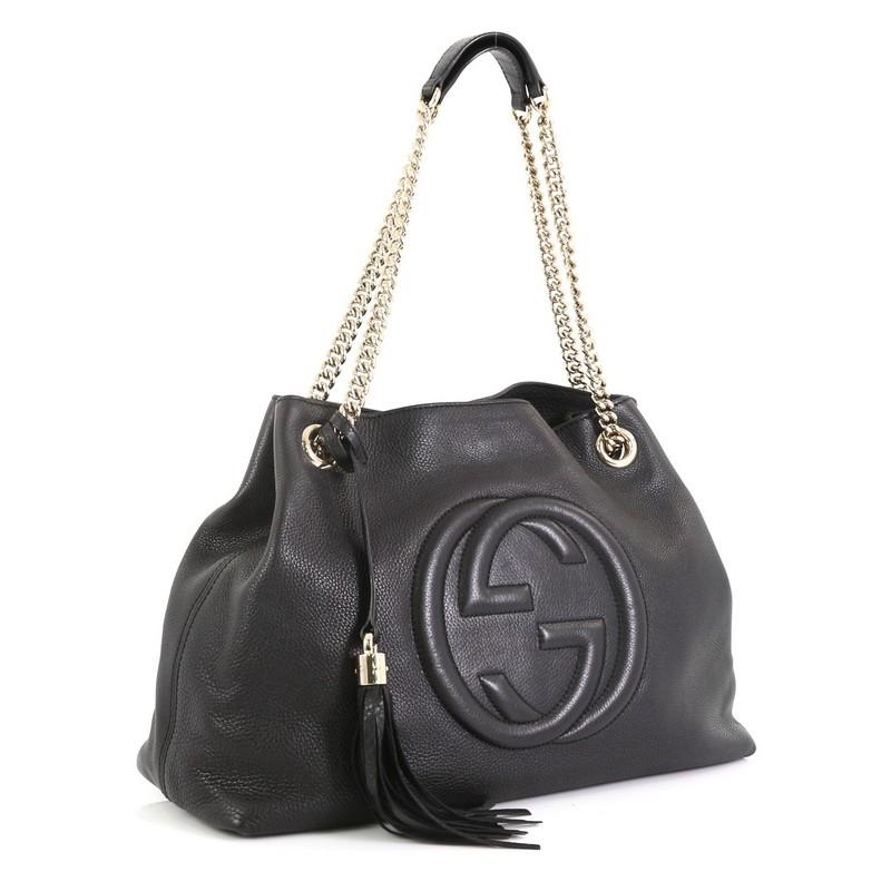 This Gucci Soho Chain Strap Shoulder Bag Leather Medium, crafted in black leather, features chain link straps with leather pads and gold-tone hardware. Its hook clasp closure opens to a neutral fabric interior with side zip and slip pockets.