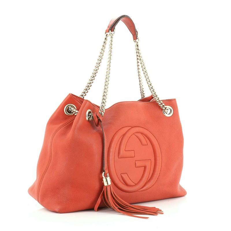 This Gucci Soho Chain Strap Shoulder Bag Leather Medium, crafted in orange leather, features chain link straps with leather pads and gold-tone hardware. Its hook clasp closure opens to a neutral canvas interior with side zip and slip pockets.