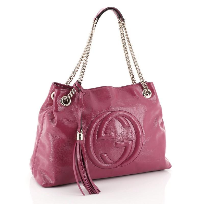 This Gucci Soho Chain Strap Shoulder Bag Patent Medium, crafted in pink patent leather, features chain link straps with leather pads and gold-tone hardware. Its hook clasp closure opens to a neutral fabric interior with side zip and slip