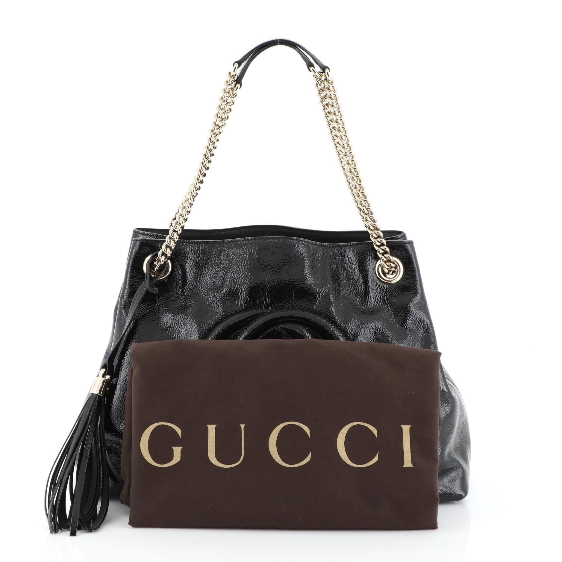 This Gucci Soho Chain Strap Shoulder Bag Patent Medium, crafted in black patent leather, features chain link straps with leather pads and gold-tone hardware. Its hook clasp closure opens to a neutral fabric interior with side zip and slip pockets.