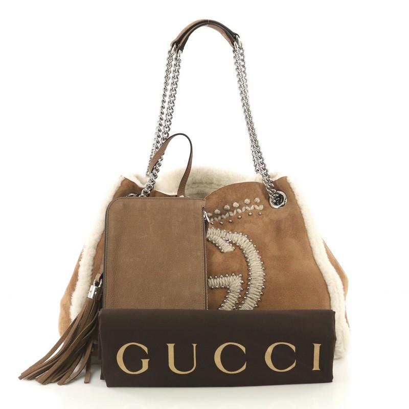 This Gucci Soho Chain Strap Shoulder Bag Studded Suede with Shearling Medium, crafted from beige suede with shearling, features chain straps with shoulder pads, fringe tassel, interlocking Gucci logo embroidered in front, wool embroidery, stud