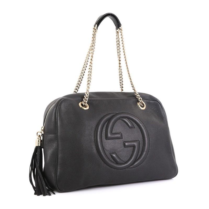 This Gucci Soho Chain Zip Shoulder Bag Leather Medium, crafted in black leather, features chain link straps with leather pads, tassel zipper pull, and gold-tone hardware. Its zip closure opens to a neutral fabric interior with side zip and slip